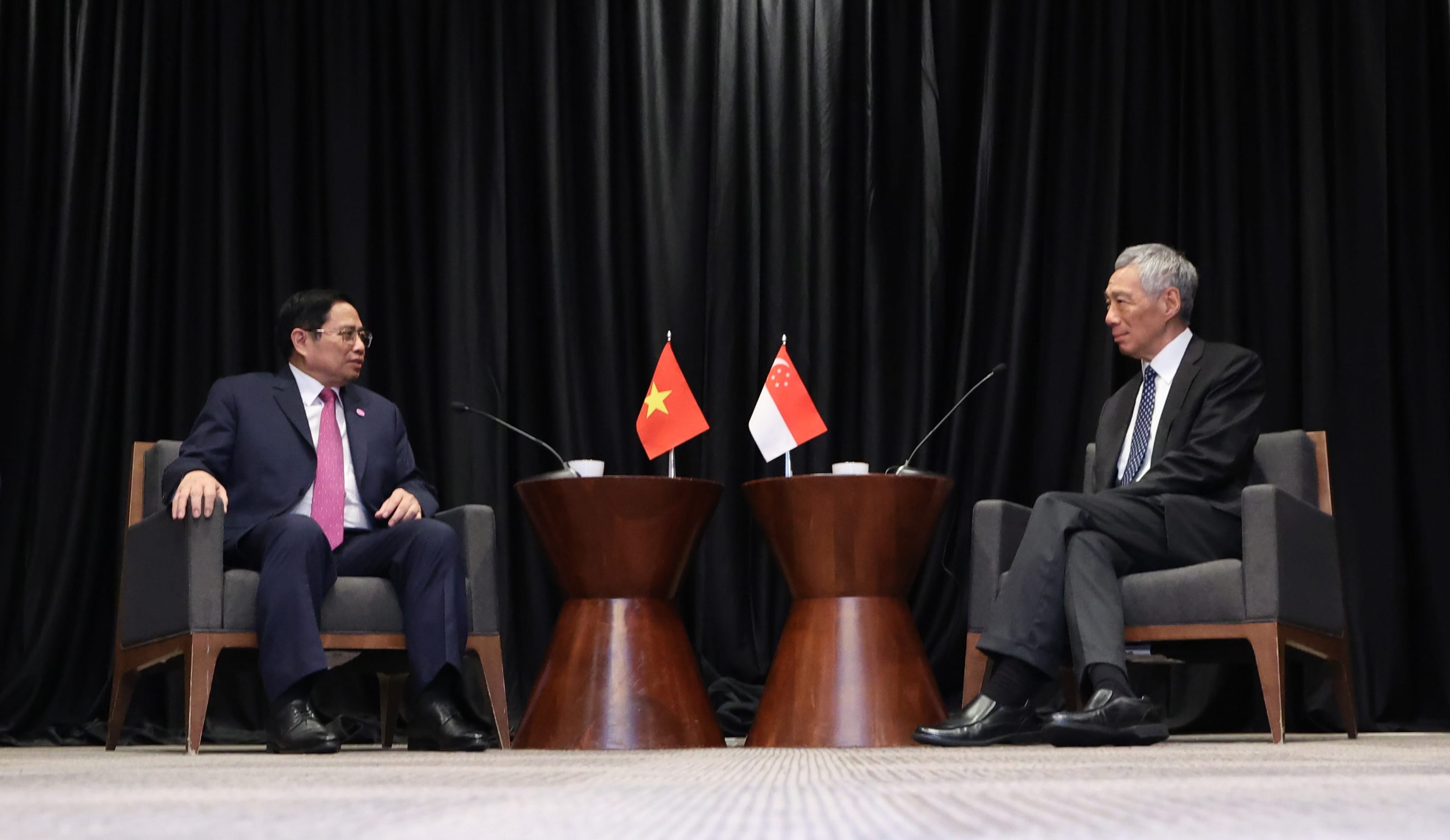 Pham Minh Chinh and Lee Hsien Loong seated with flags of Vietnam and Singapore between them.