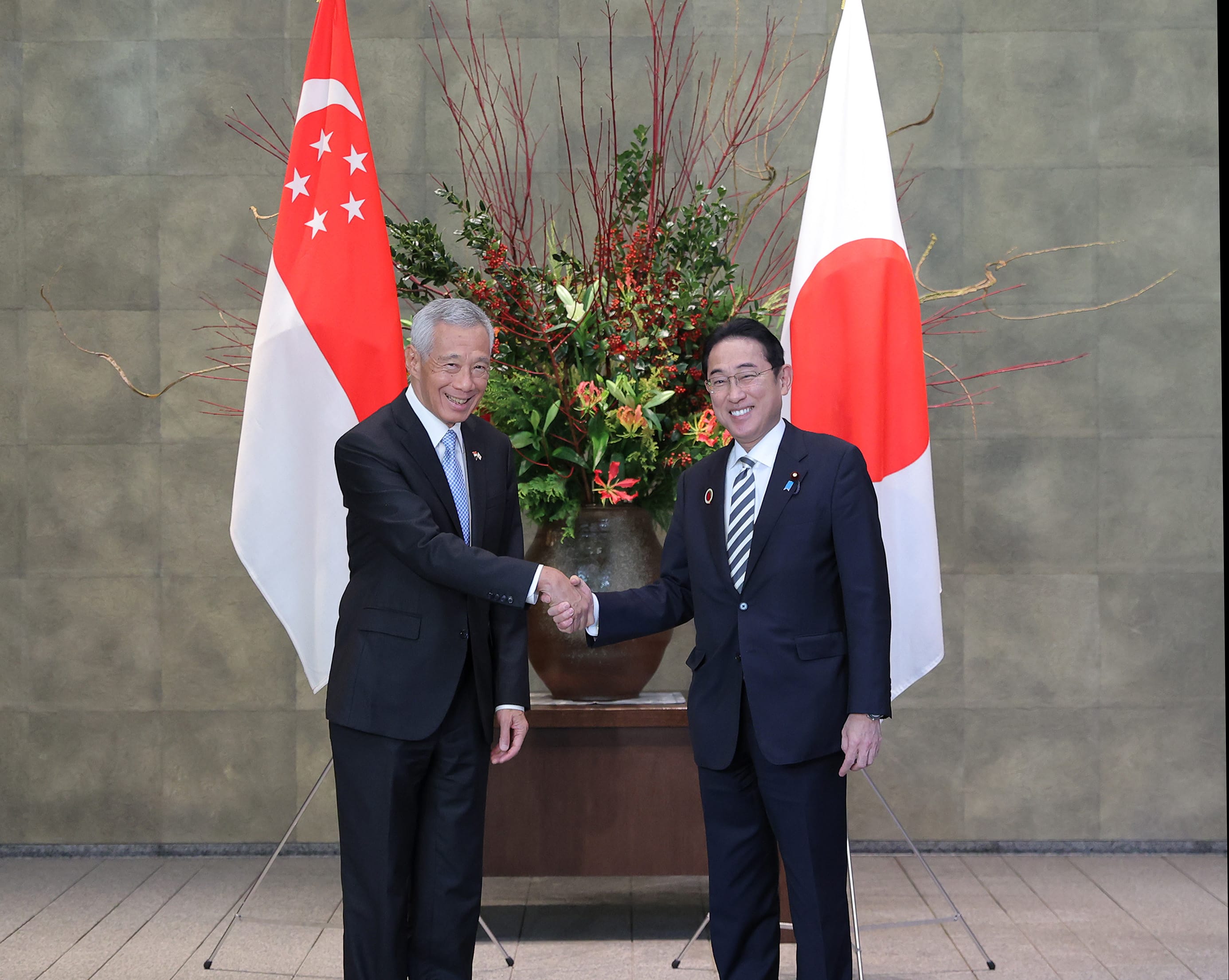 Lee Hsien Loong and Fumio Kishida shake hands; Singapore and Japan flags in the background.