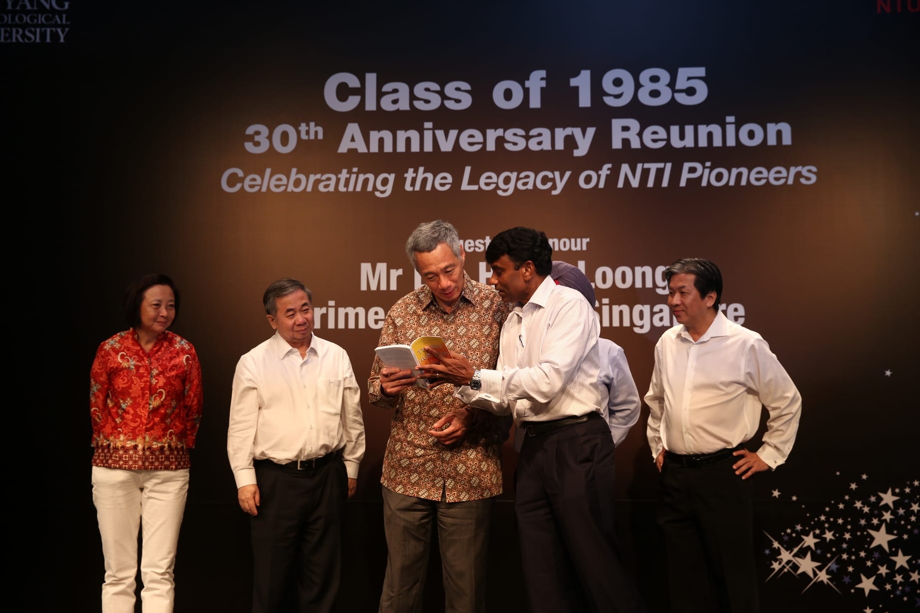 NTU Class of 1985 reunion, with Prime Minister Lee Hsien Loong looking at a book held by another man.