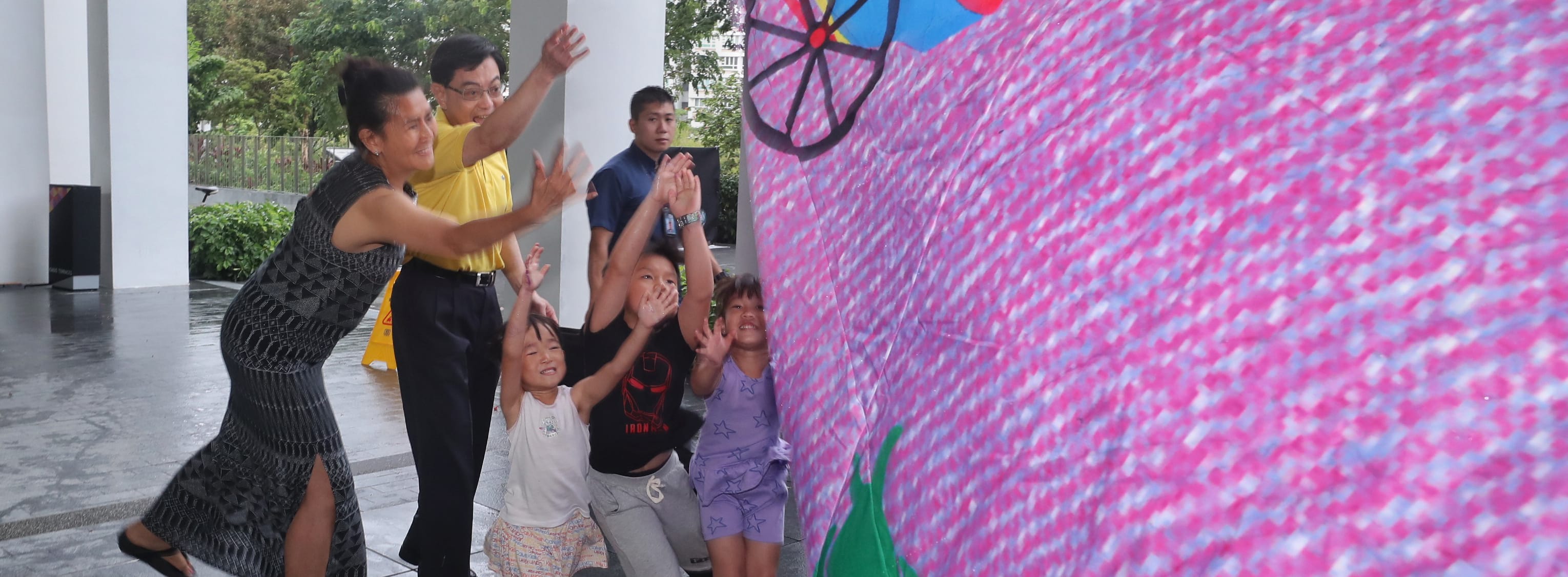 Group with hands raised next to a painted backdrop.