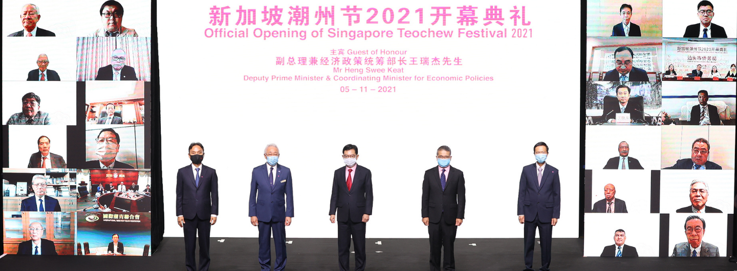 Singapore Teochew Festival opening with speakers on screens and people in suits on stage.