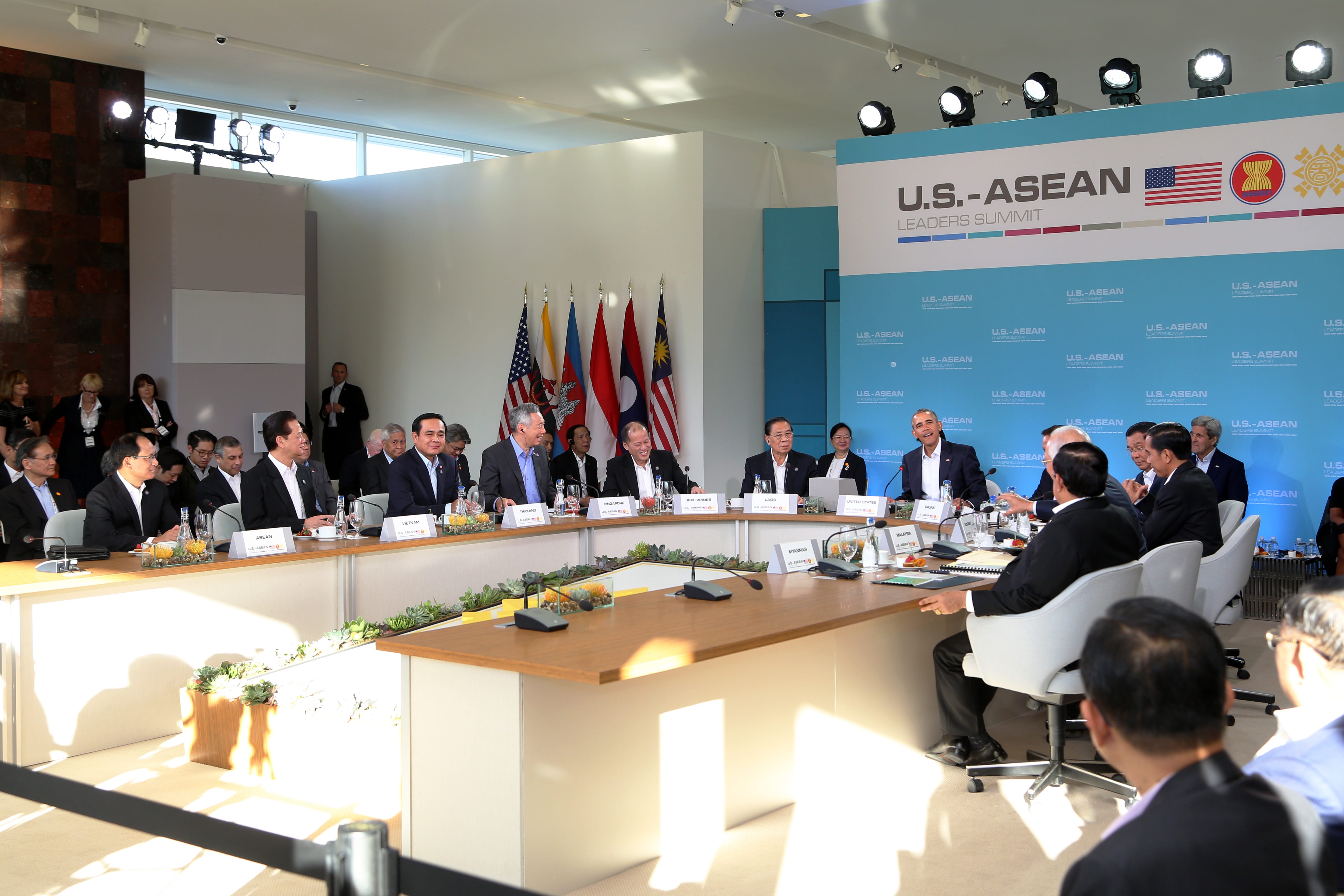 Leaders at U.S.-ASEAN Summit around a table with country placards and flags.