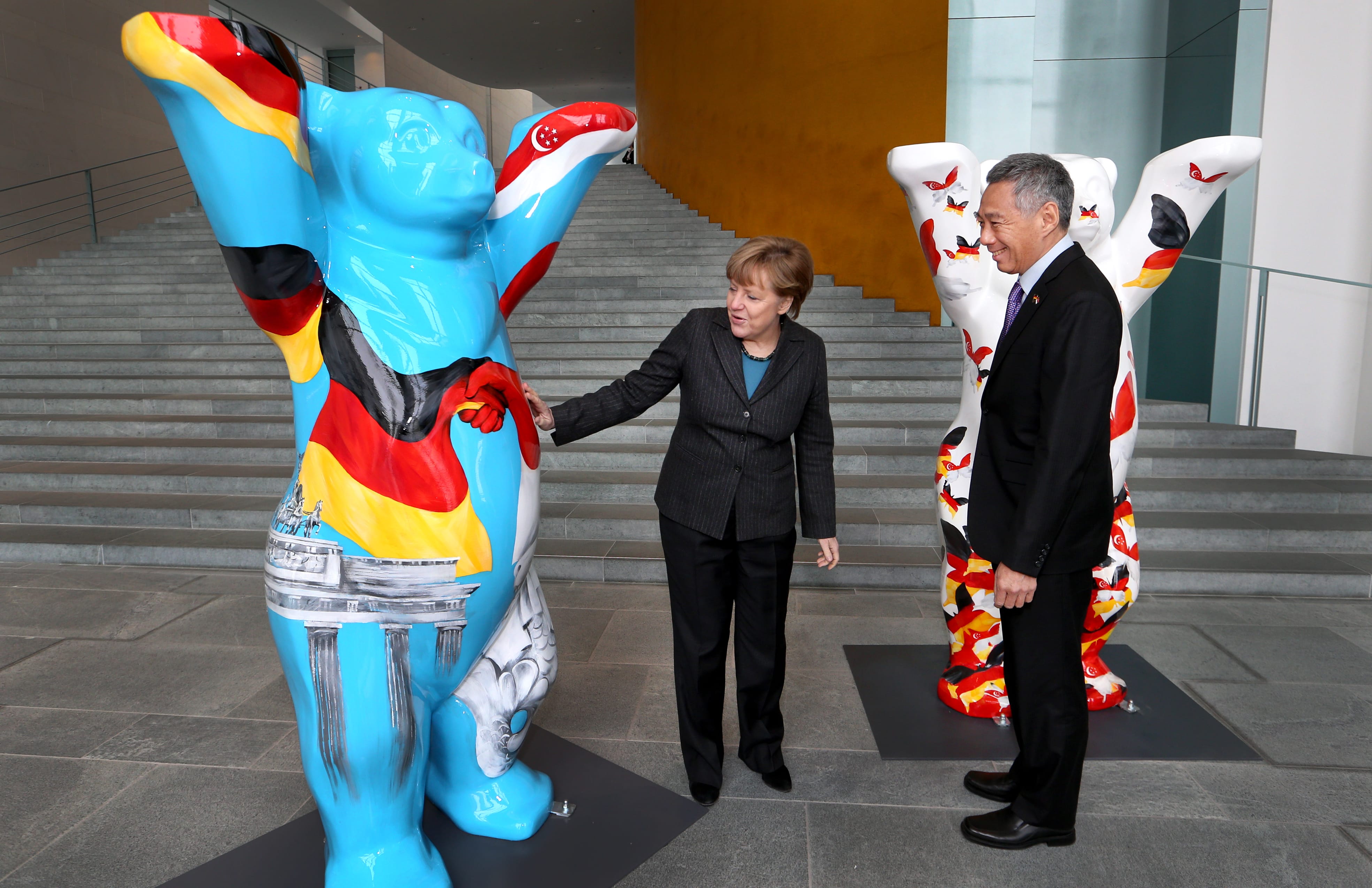 Angela Merkel and Lee Hsien Loong with Buddy Bears; Merkel touching one painted with German flag.