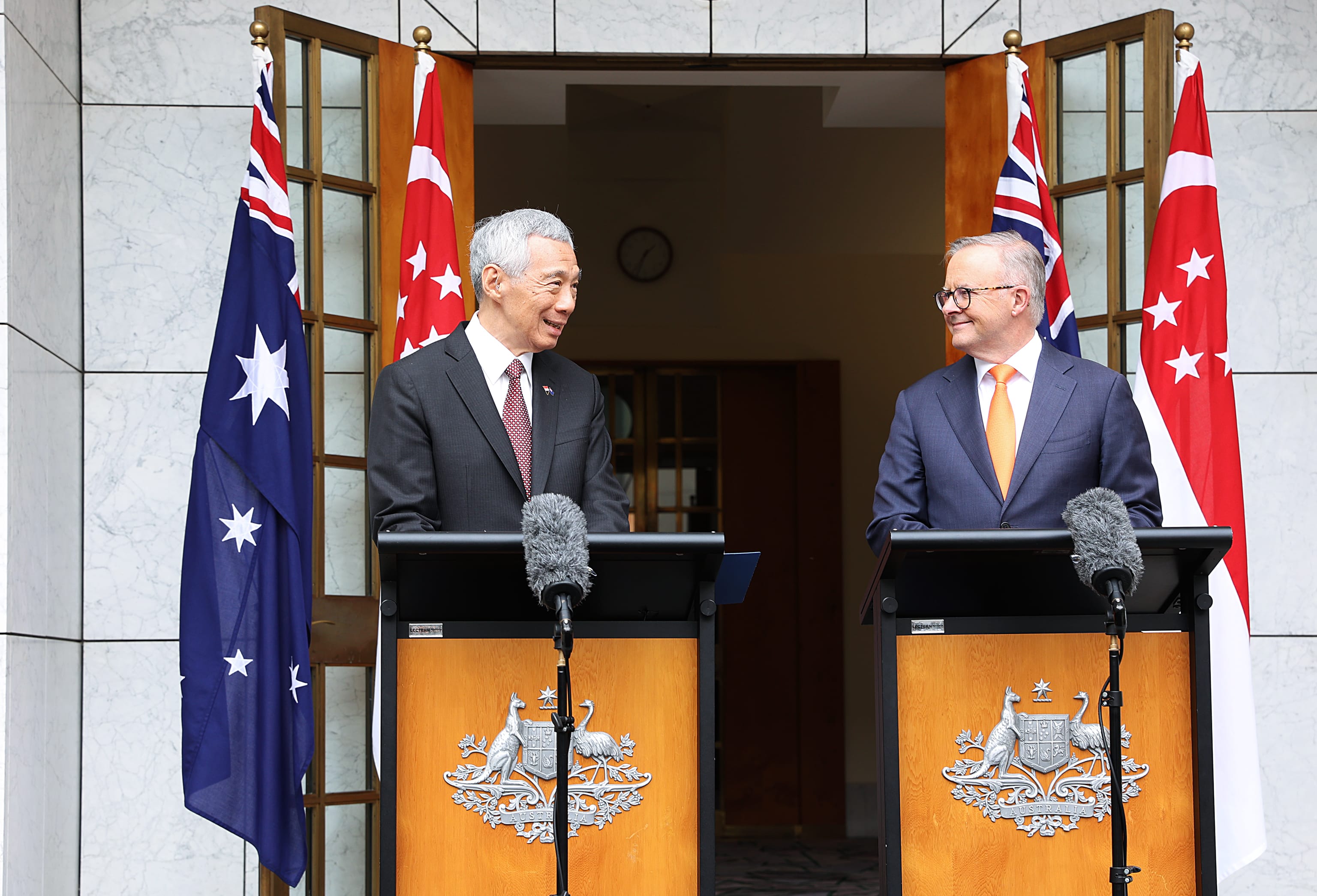 Lee Hsien Loong and Anthony Albanese at lecterns with flags of Singapore and Australia.