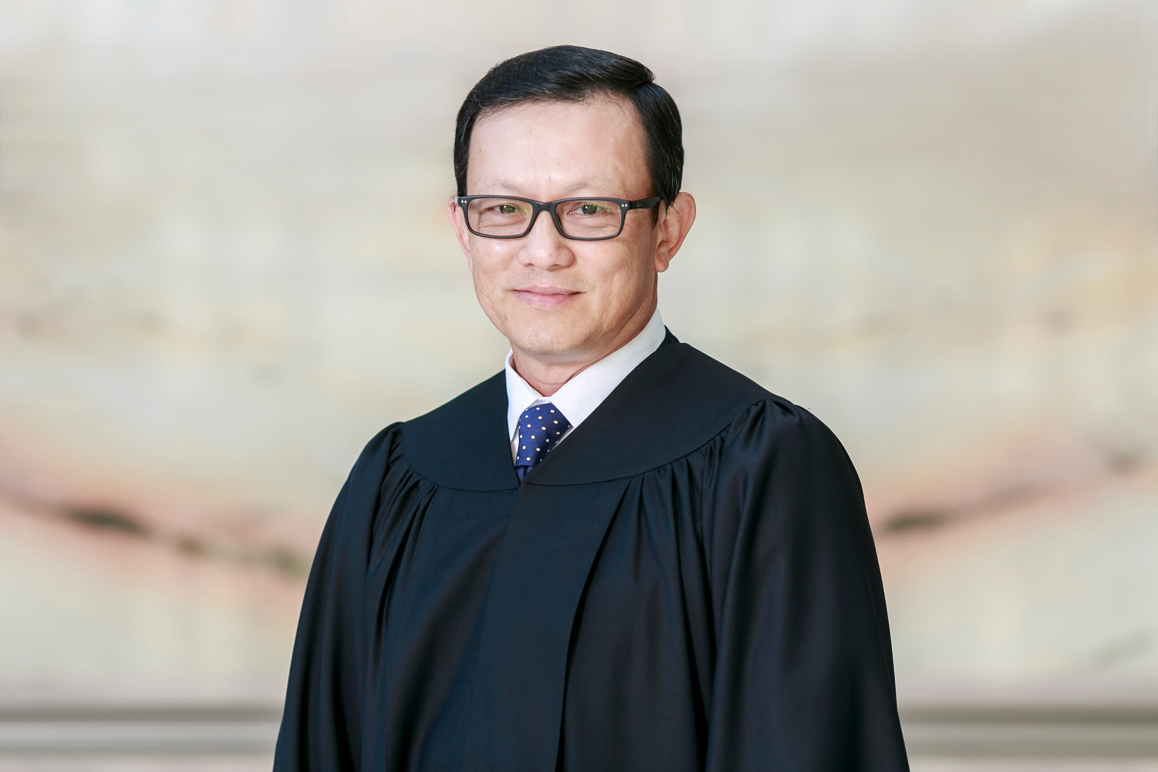 Portrait of a man wearing a black judicial robe and glasses.