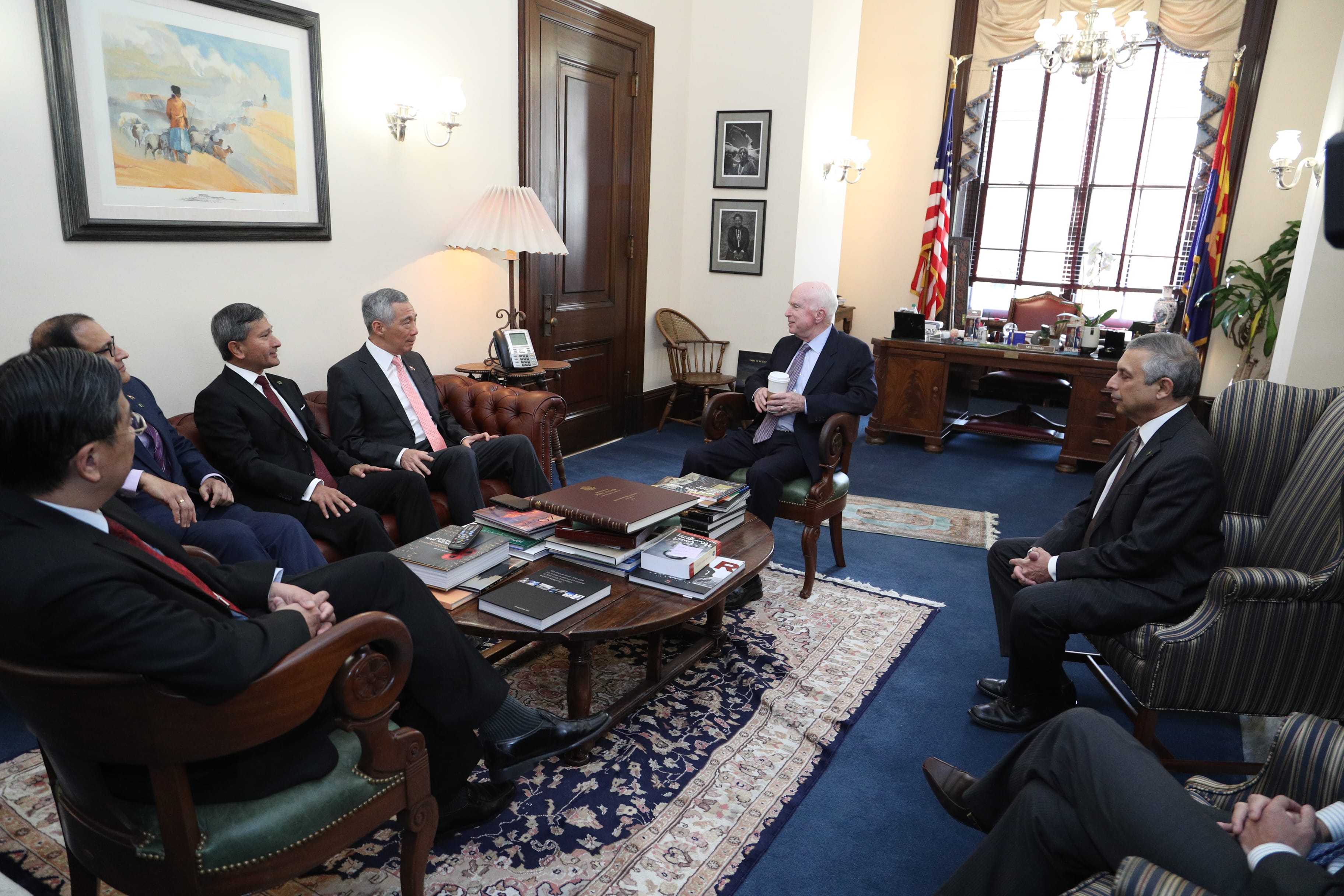Meeting with John McCain: men in suits sit in chairs around a low table in an office.