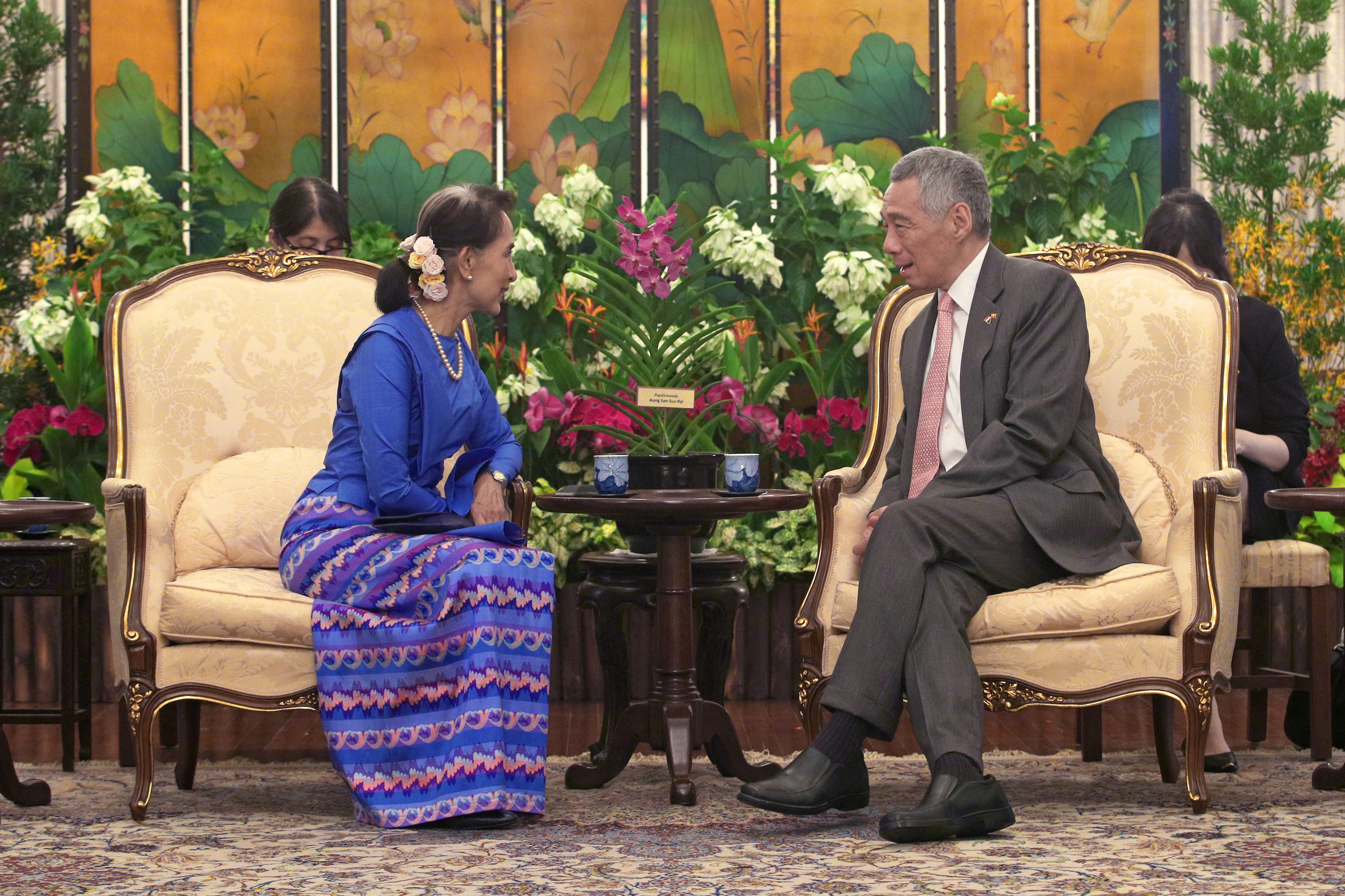 Aung San Suu Kyi & Lee Hsien Loong seated in ornate chairs, facing each other in conversation.