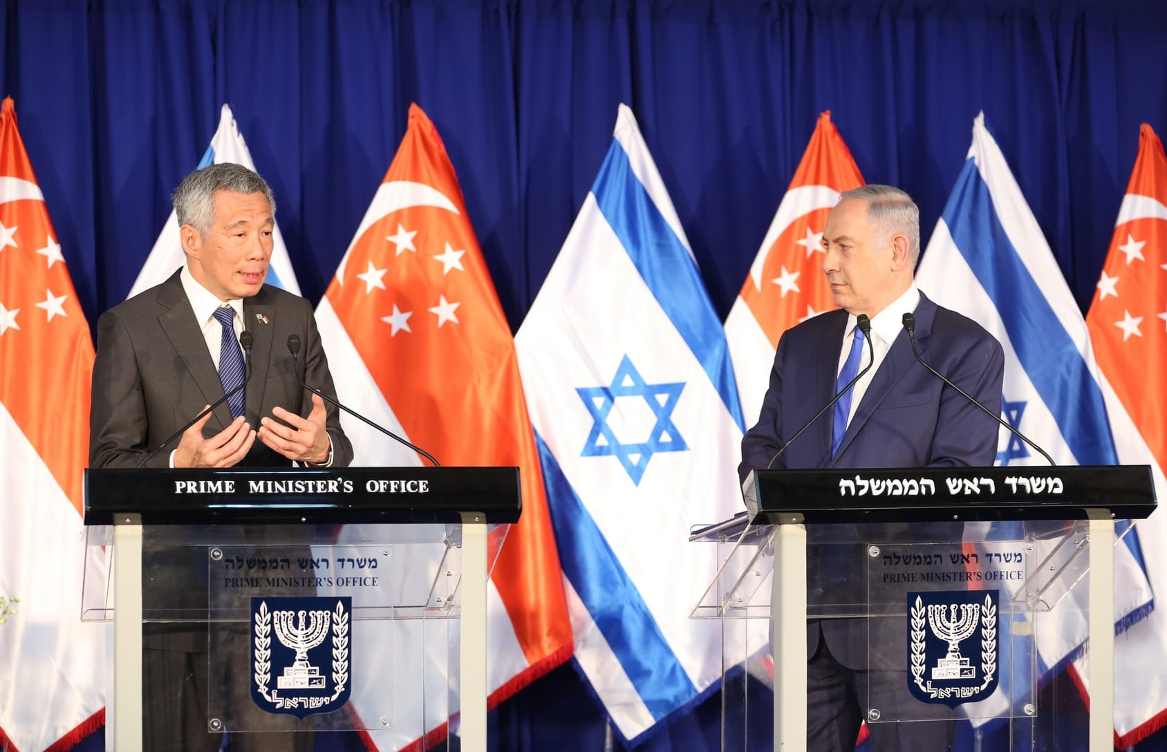 Lee Hsien Loong and Benjamin Netanyahu at podiums with Singaporean and Israeli flags behind them.