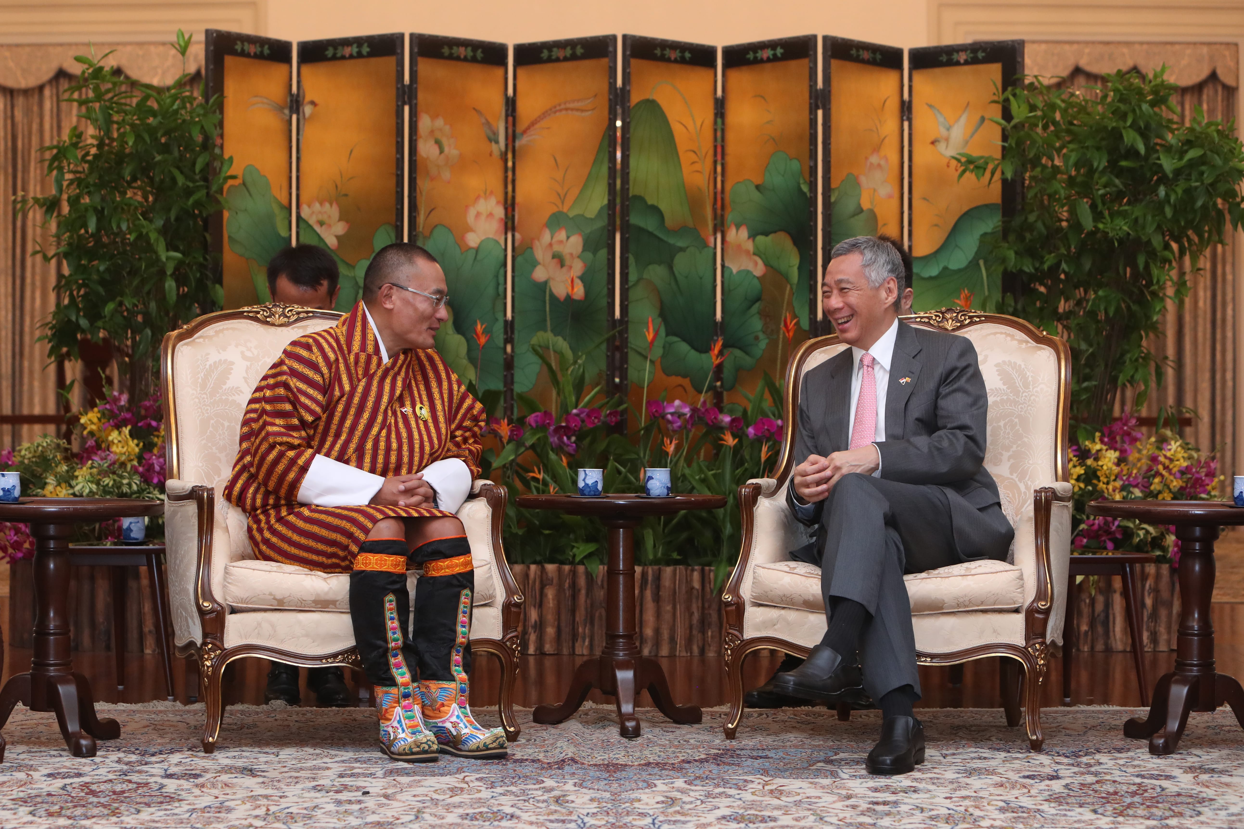 Bhutan's king in traditional dress, and Singapore's Prime Minister Lee, sit facing each other and talking.
