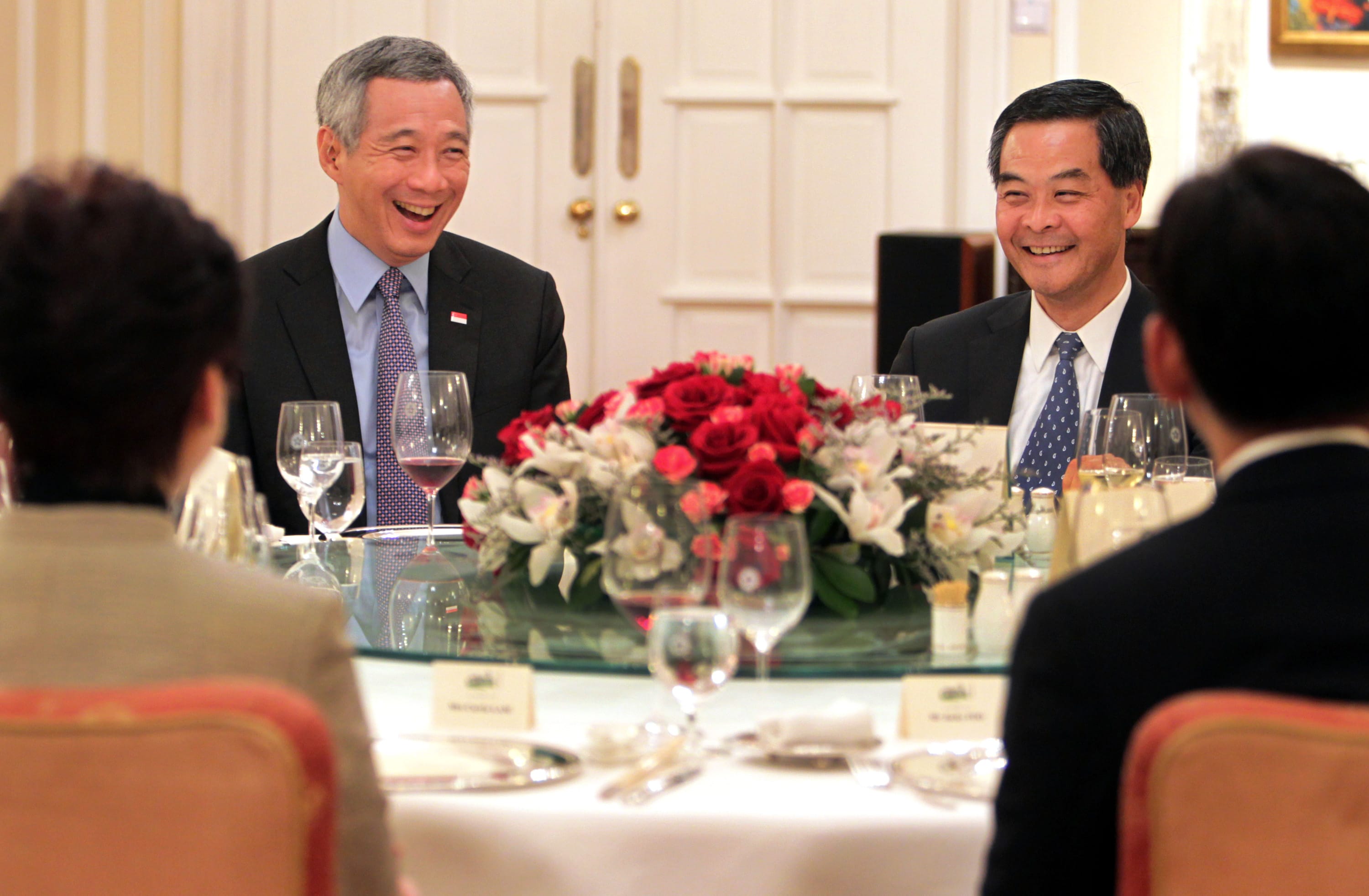 Lee Hsien Loong and another man smile at a formal dinner.
