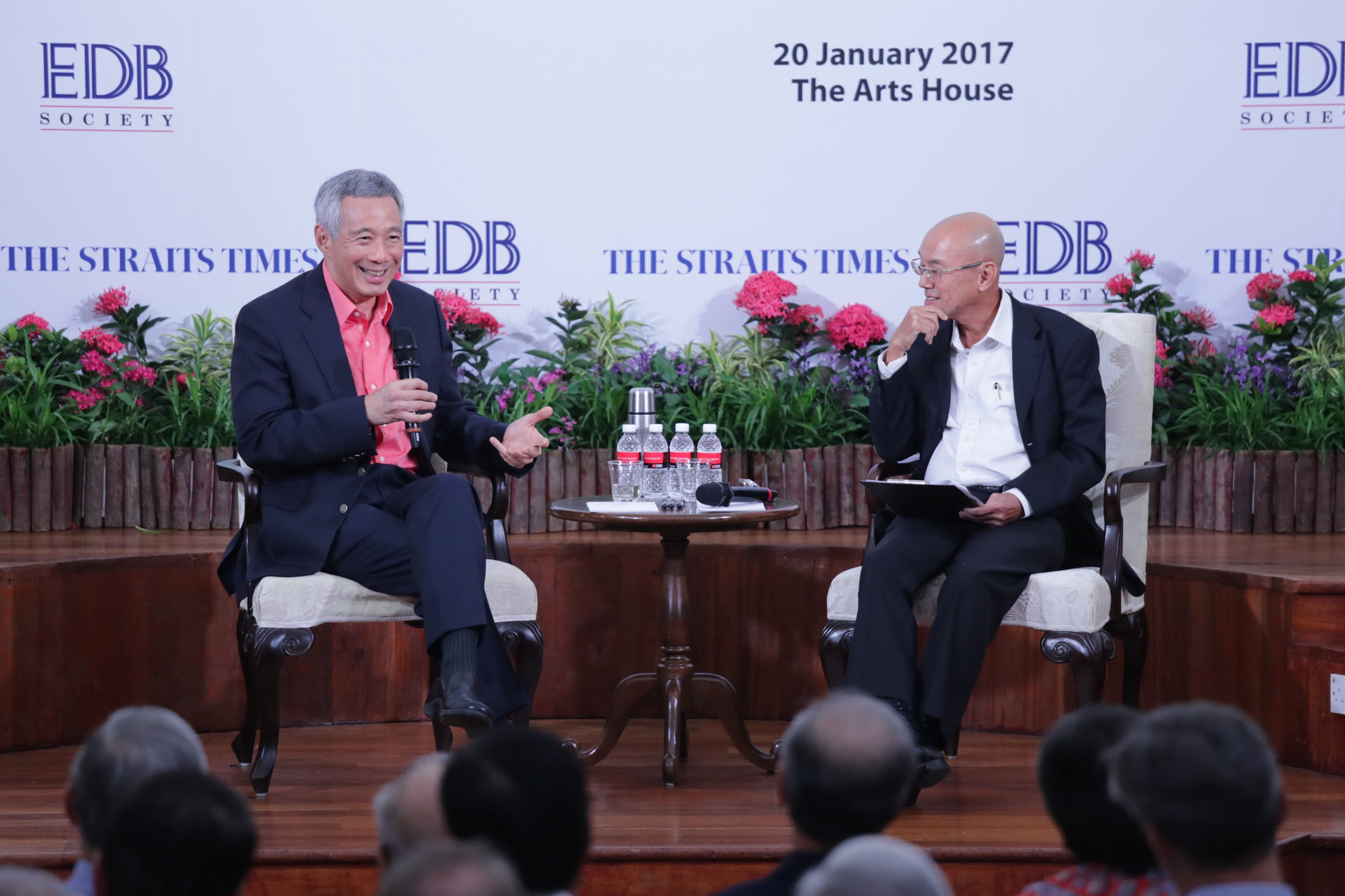 Two men seated on stage at an event; Lee Hsien Loong speaks at microphone.