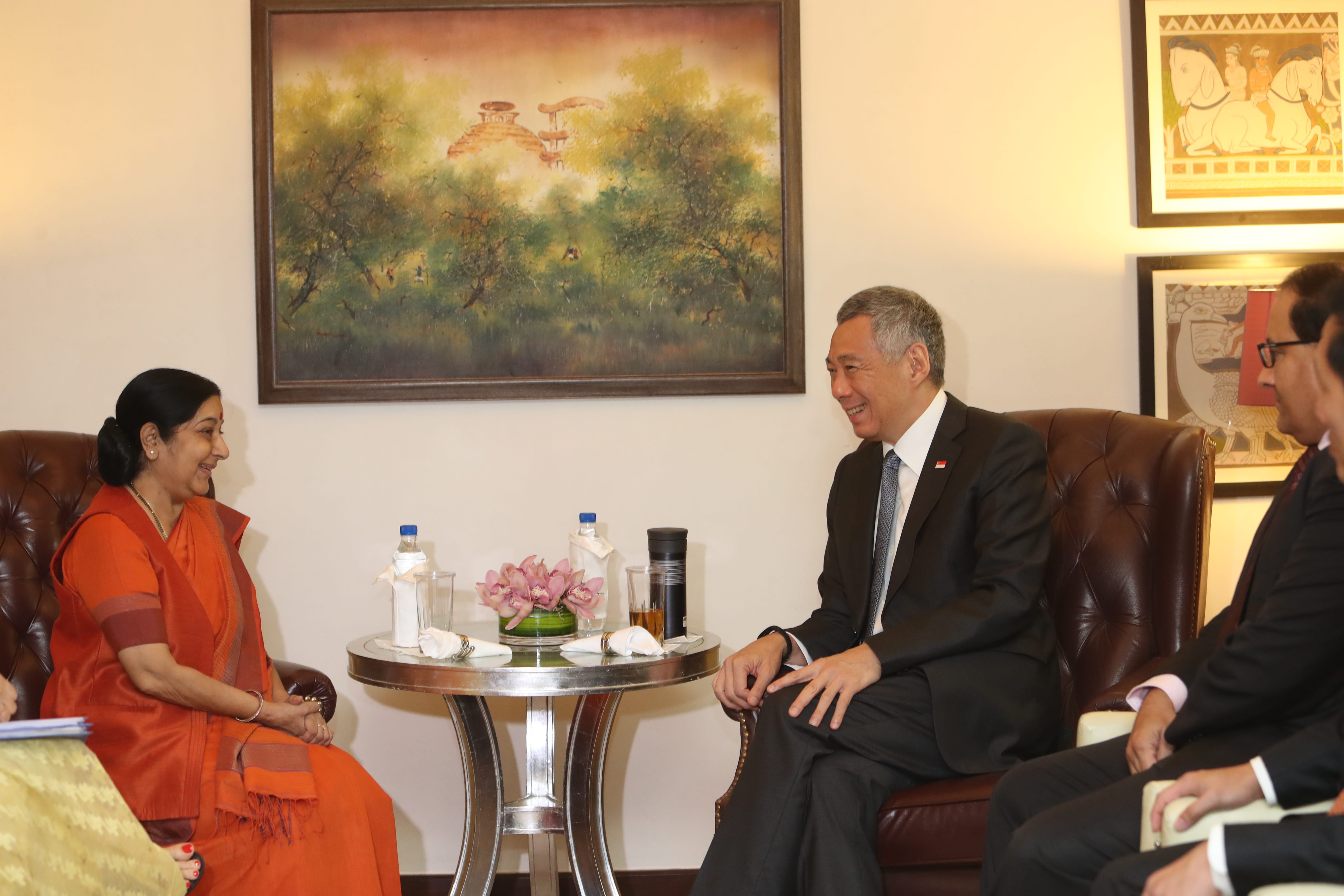 Two people in formal attire seated having a discussion in a room with art.