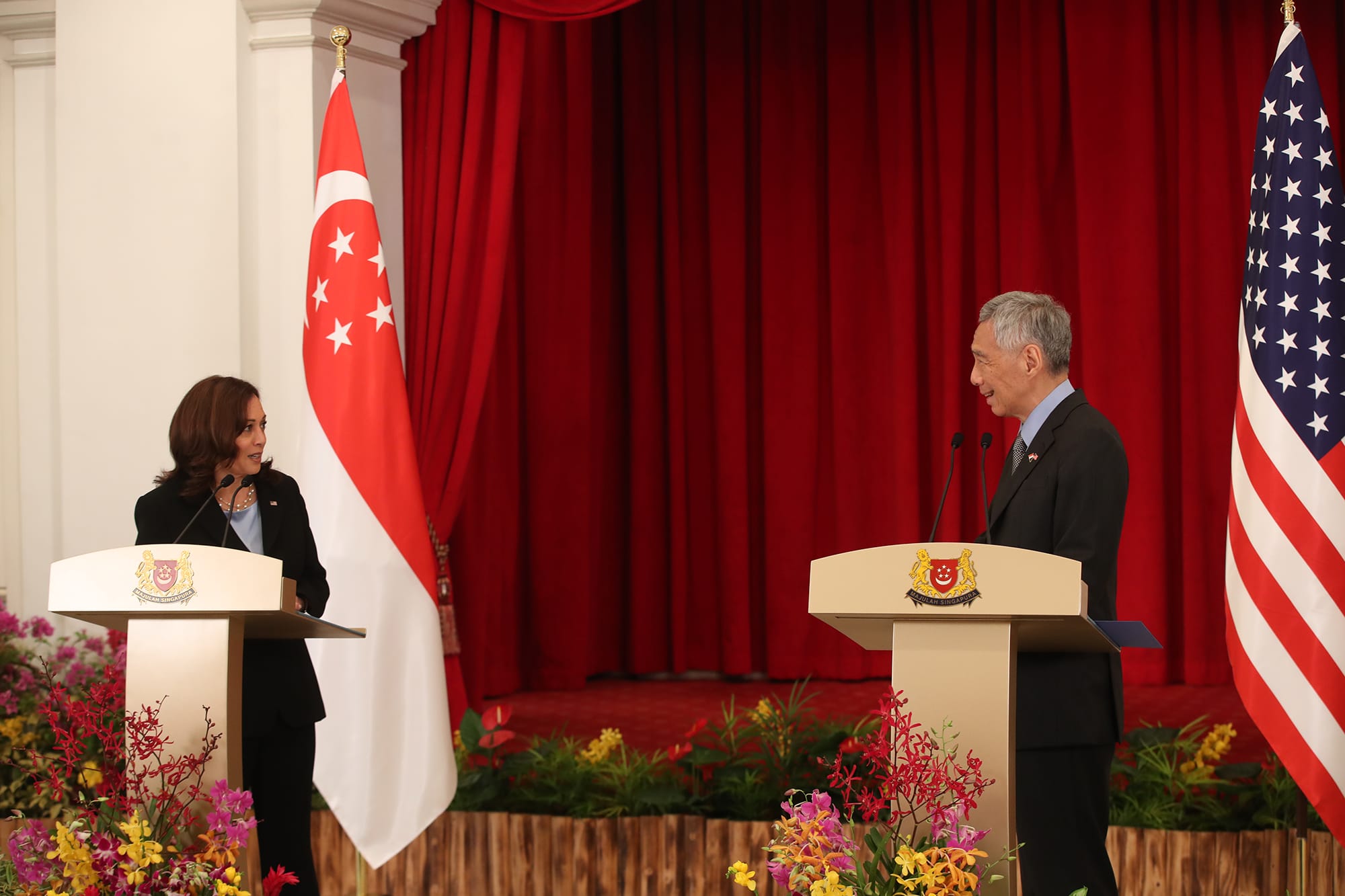 Kamala Harris and Lee Hsien Loong at podiums with US and Singapore flags.