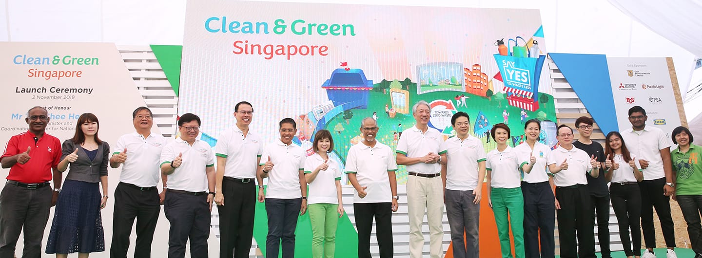 Group of people at "Clean & Green Singapore" launch ceremony giving thumbs up, with sponsor logos including IKEA.