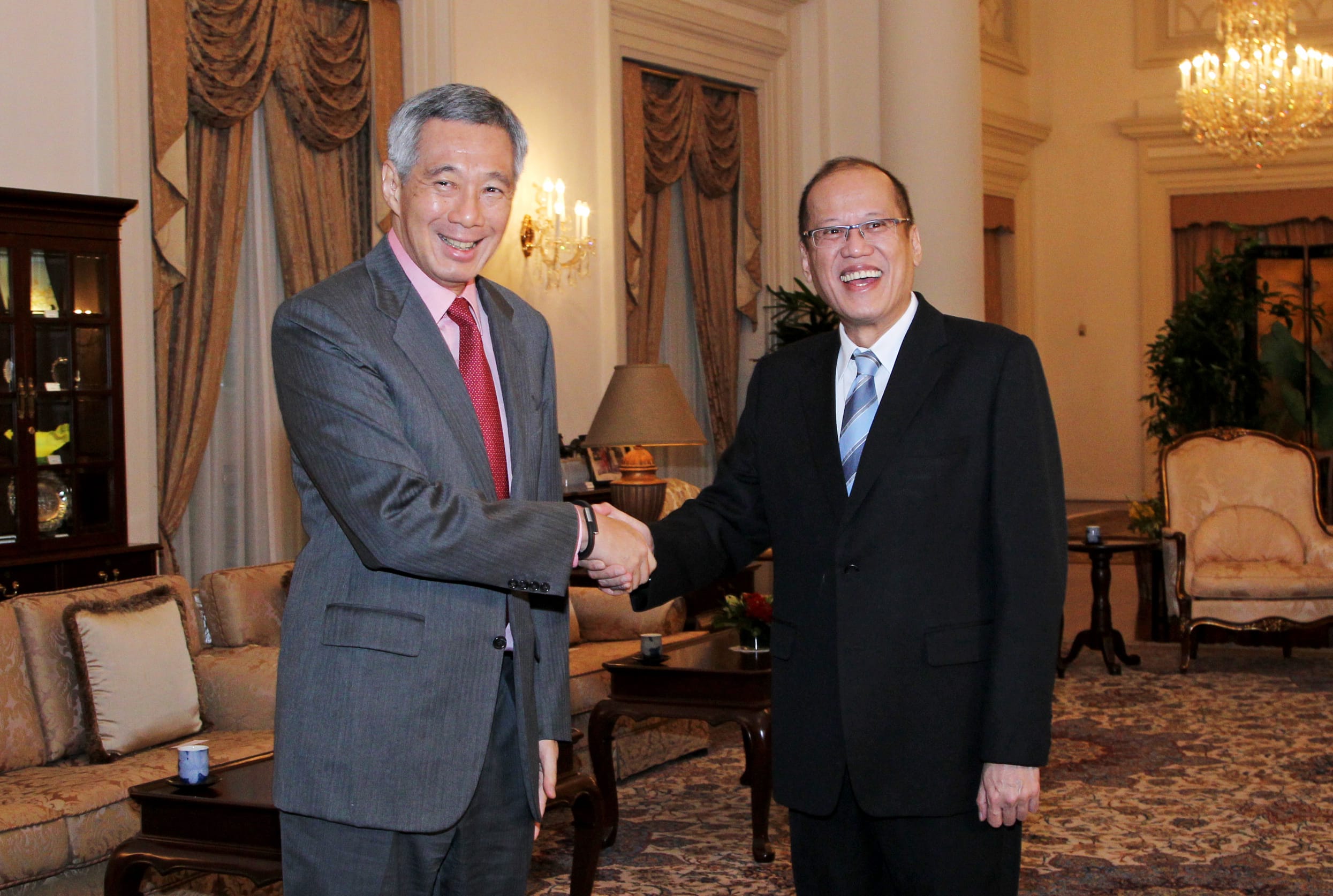Lee Hsien Loong and Benigno Aquino III shaking hands indoors, smiling.