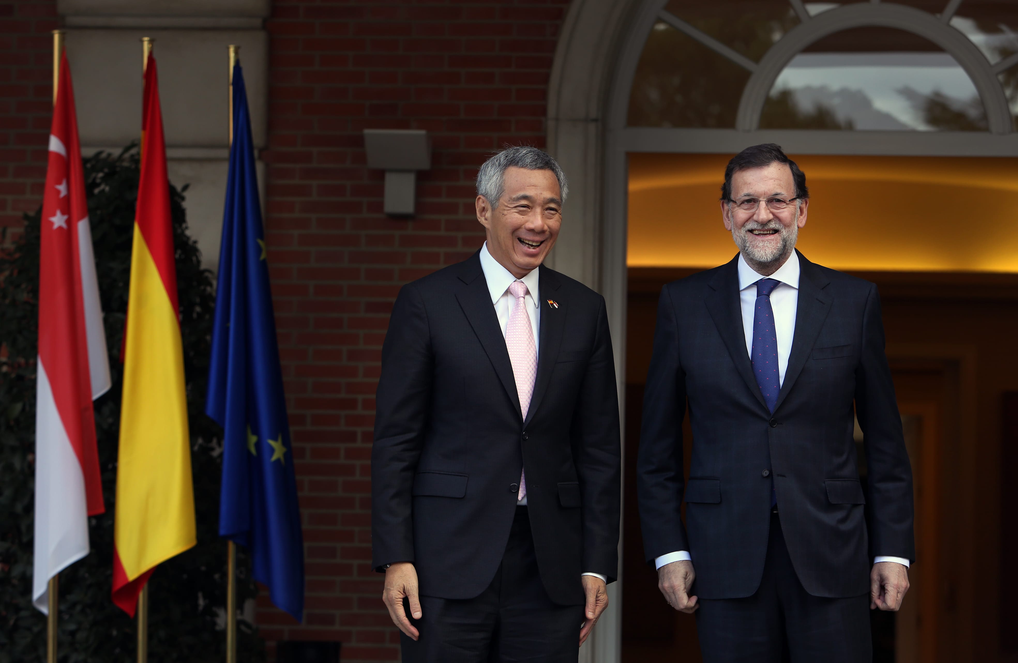 Lee Hsien Loong and Mariano Rajoy stand before flags of Singapore, Germany, and EU.