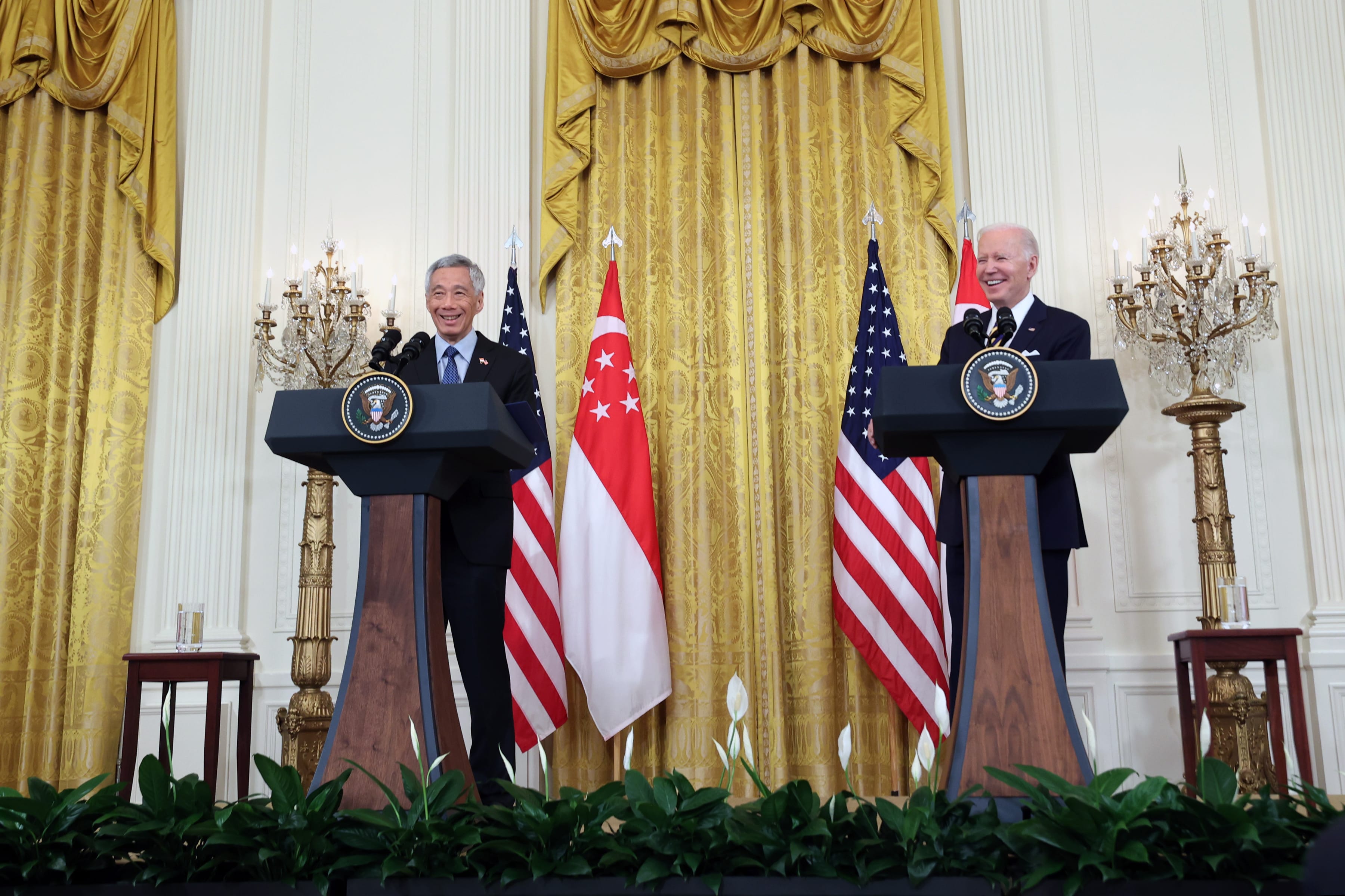 Lee Hsien Loong and Joe Biden at separate podiums in front of US and Singapore flags.