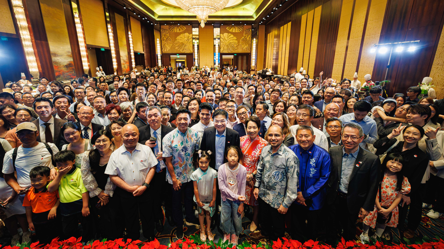 Large group of diverse people posing indoors in formal setting.