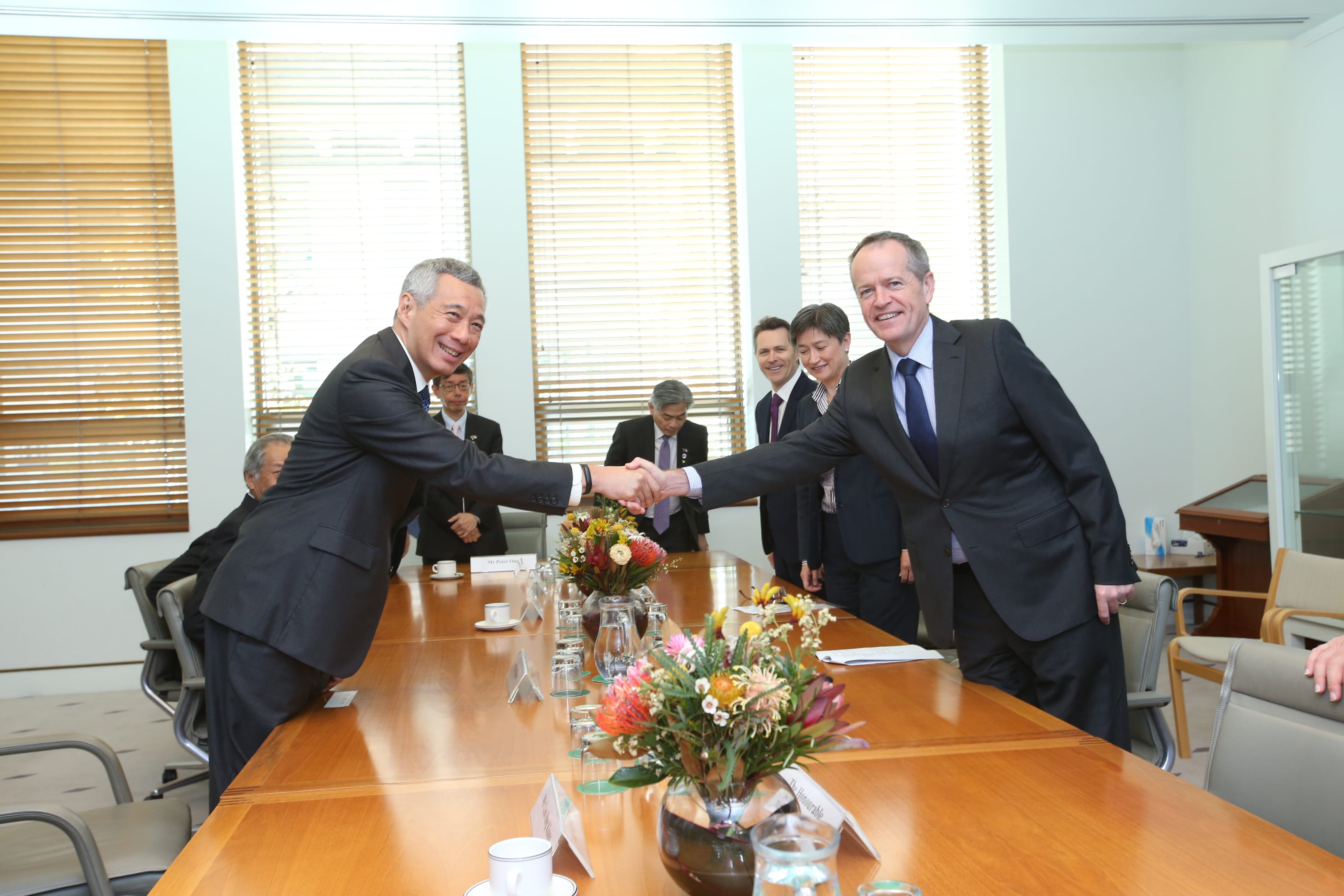 Lee Hsien Loong and Bill Shorten shake hands across a conference table.