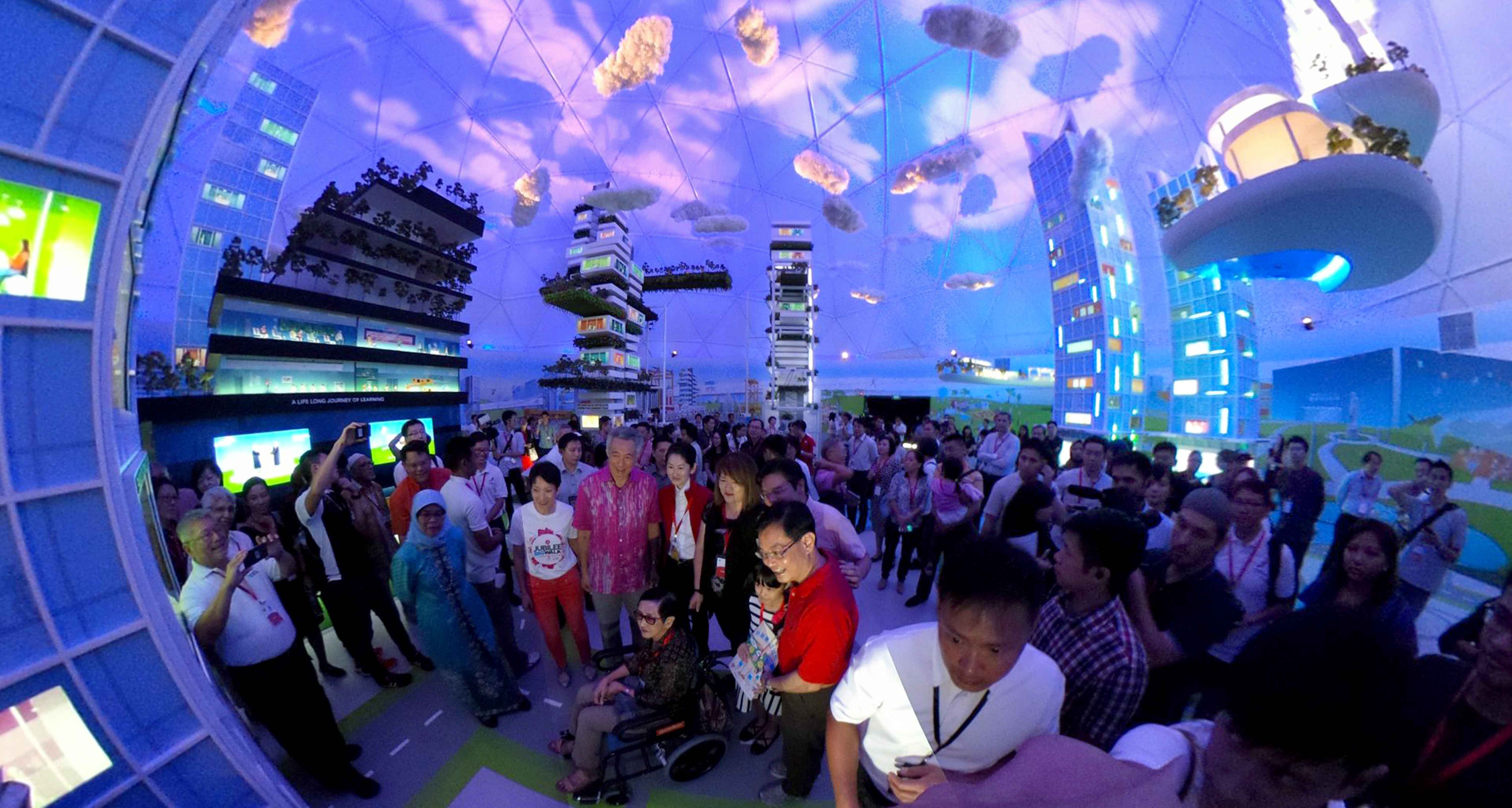 Indoor exhibit with crowds, future city models, dome ceiling, and cloud props.
