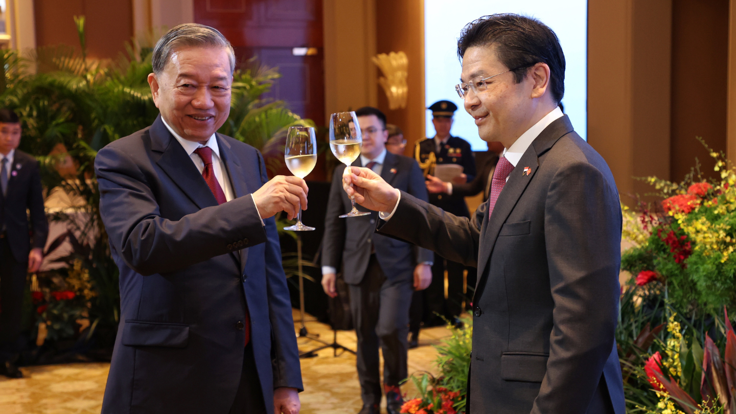 Two men in suits toasting with wine glasses at an event.