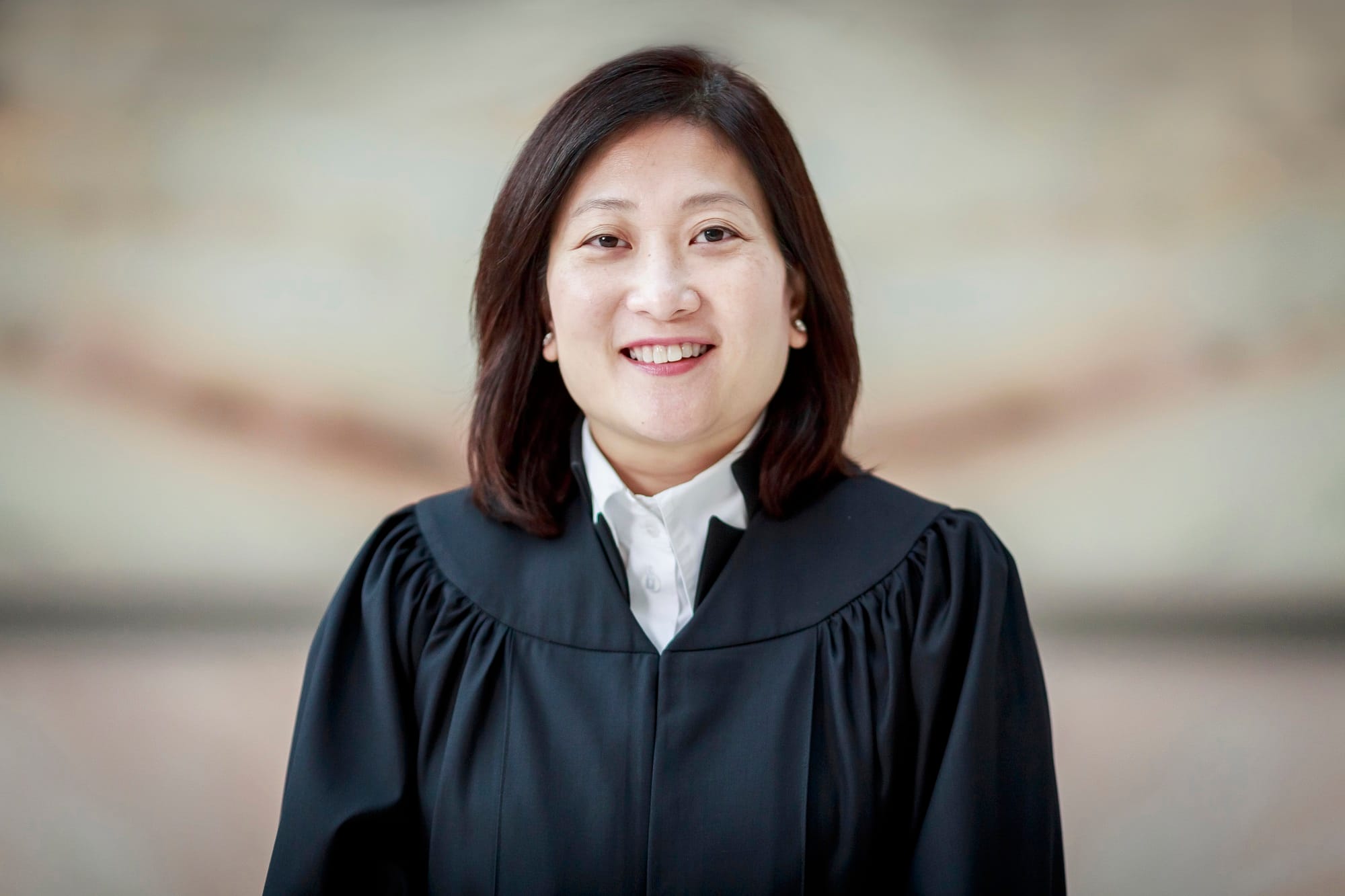 Headshot of a smiling woman wearing a black judicial robe over a white collared shirt.