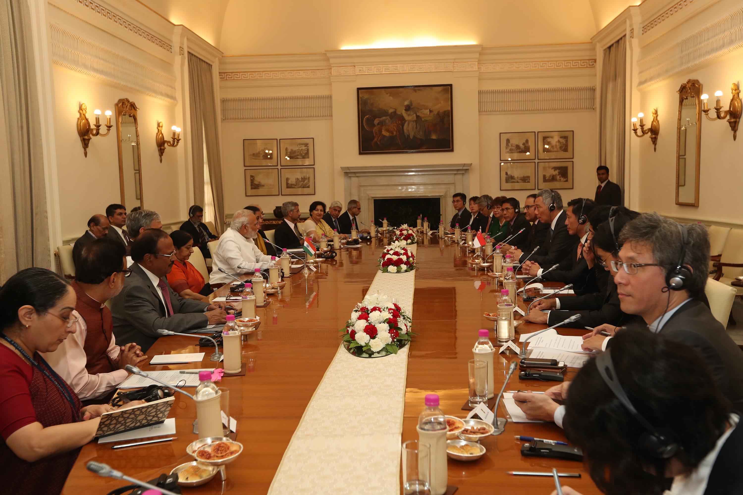 People seated at a long table decorated with flowers, microphones, and water bottles.