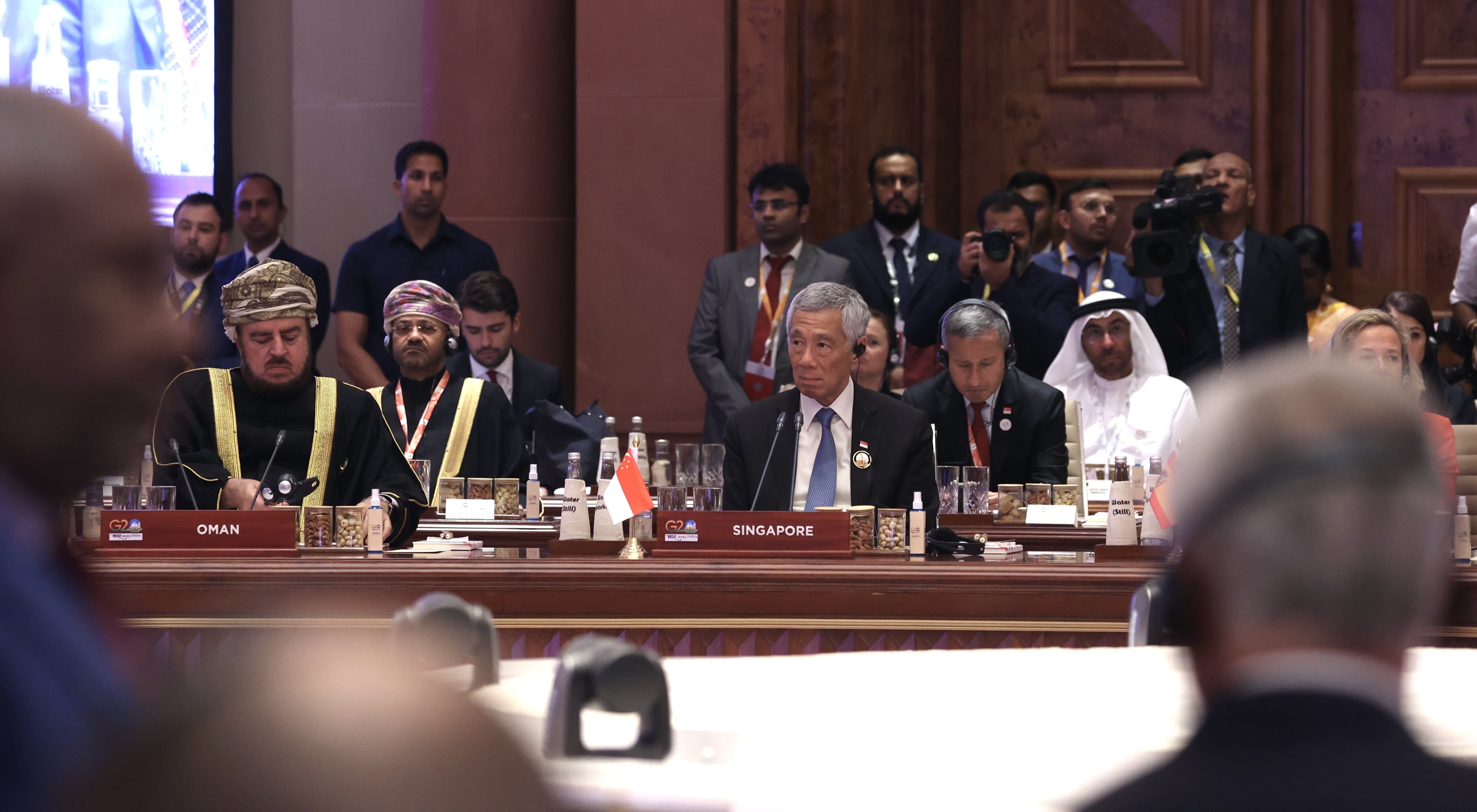 Leaders at a conference table, with flags identifying Oman and Singapore.