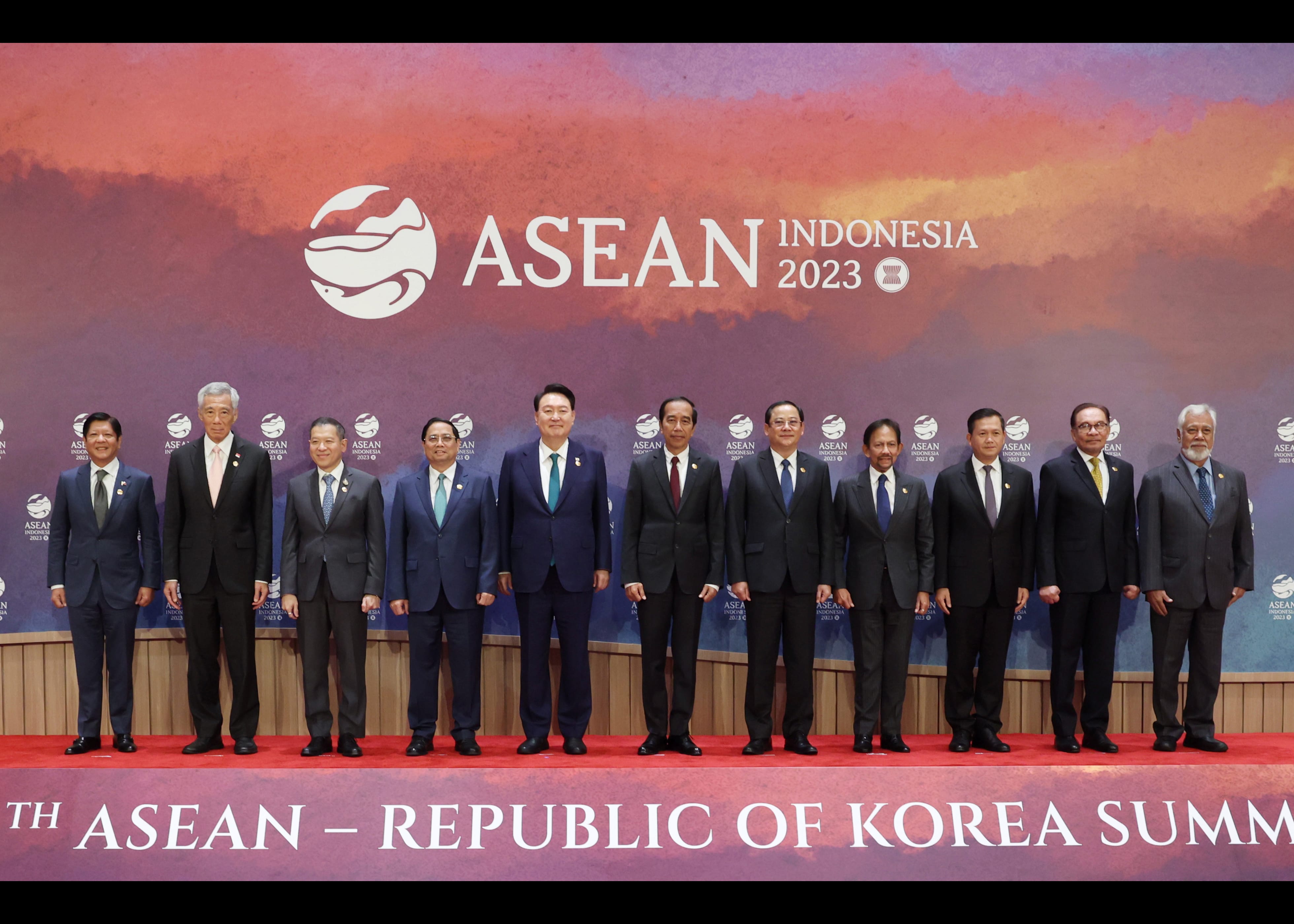 Eleven people in suits stand before "ASEAN Indonesia 2023" backdrop on a red carpet.