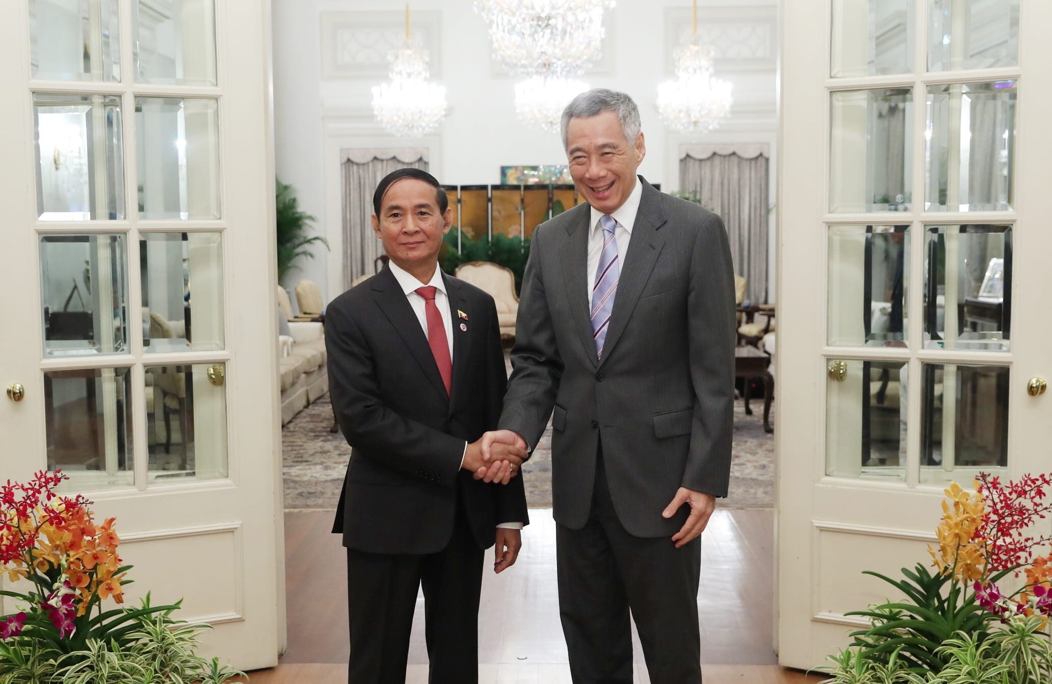 Lee Hsien Loong shaking hands with another leader in front of doors.