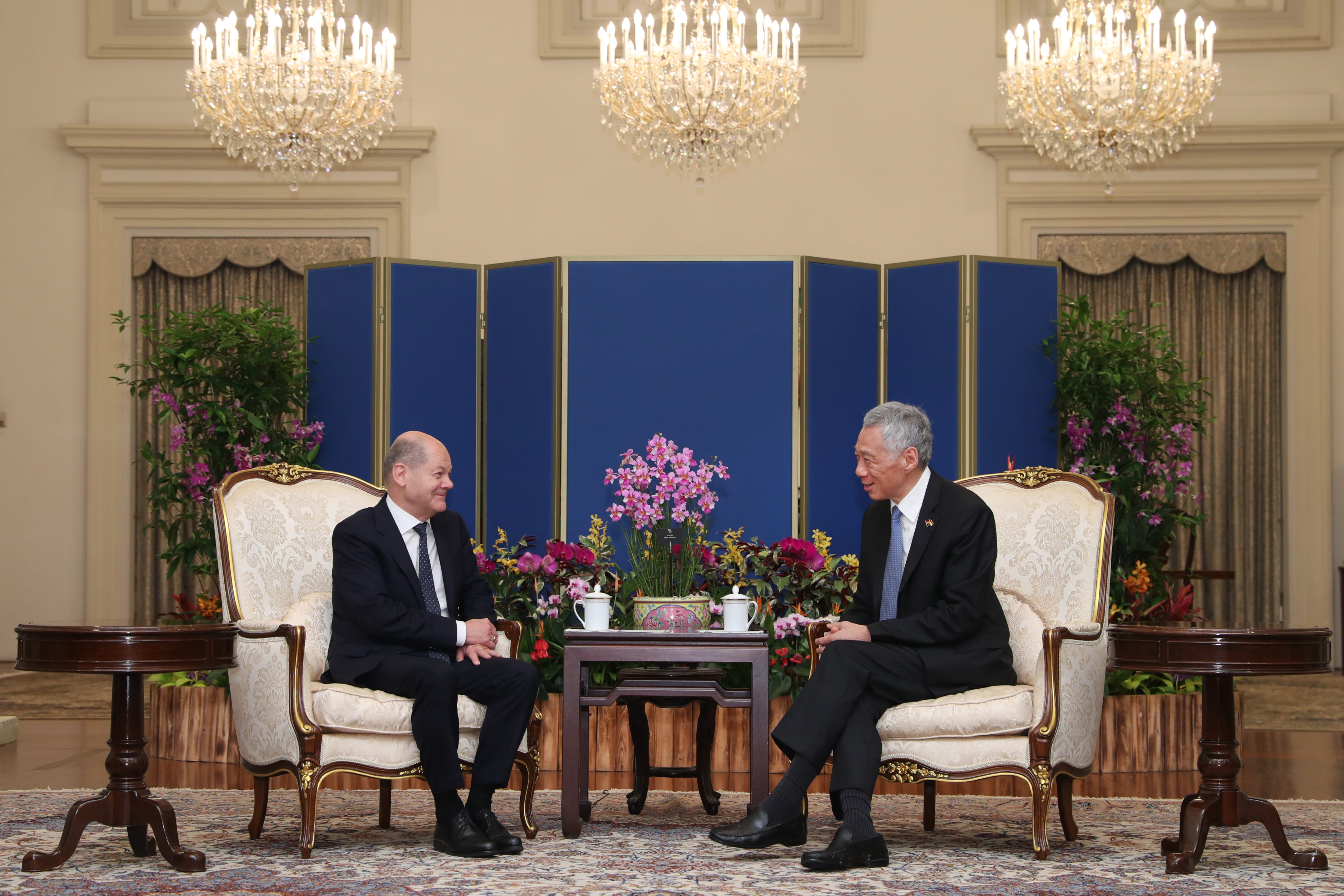 Olaf Scholz and Lee Hsien Loong sit in ornate chairs facing each other in a formal room.