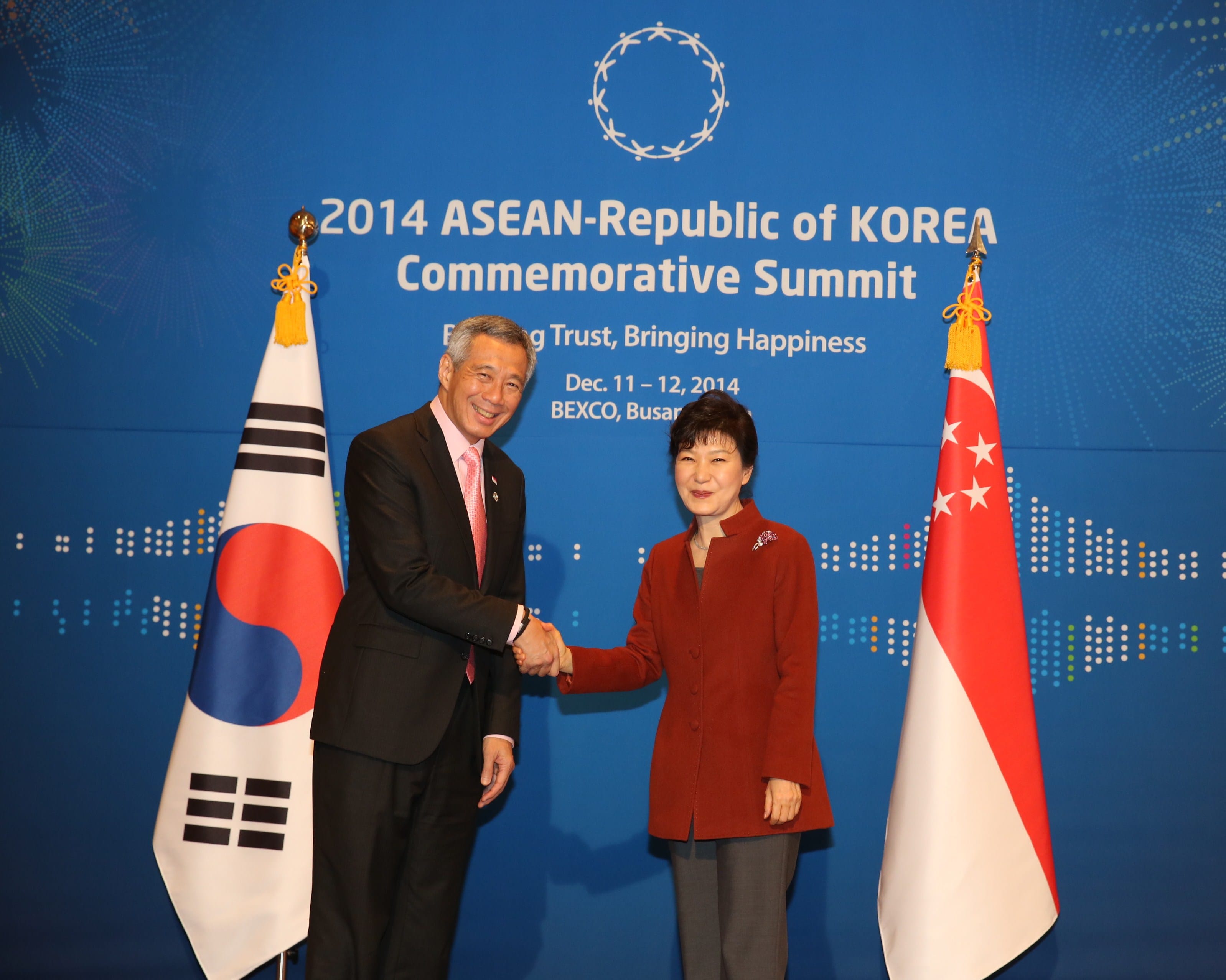Two leaders shake hands between the flags of South Korea and Singapore.