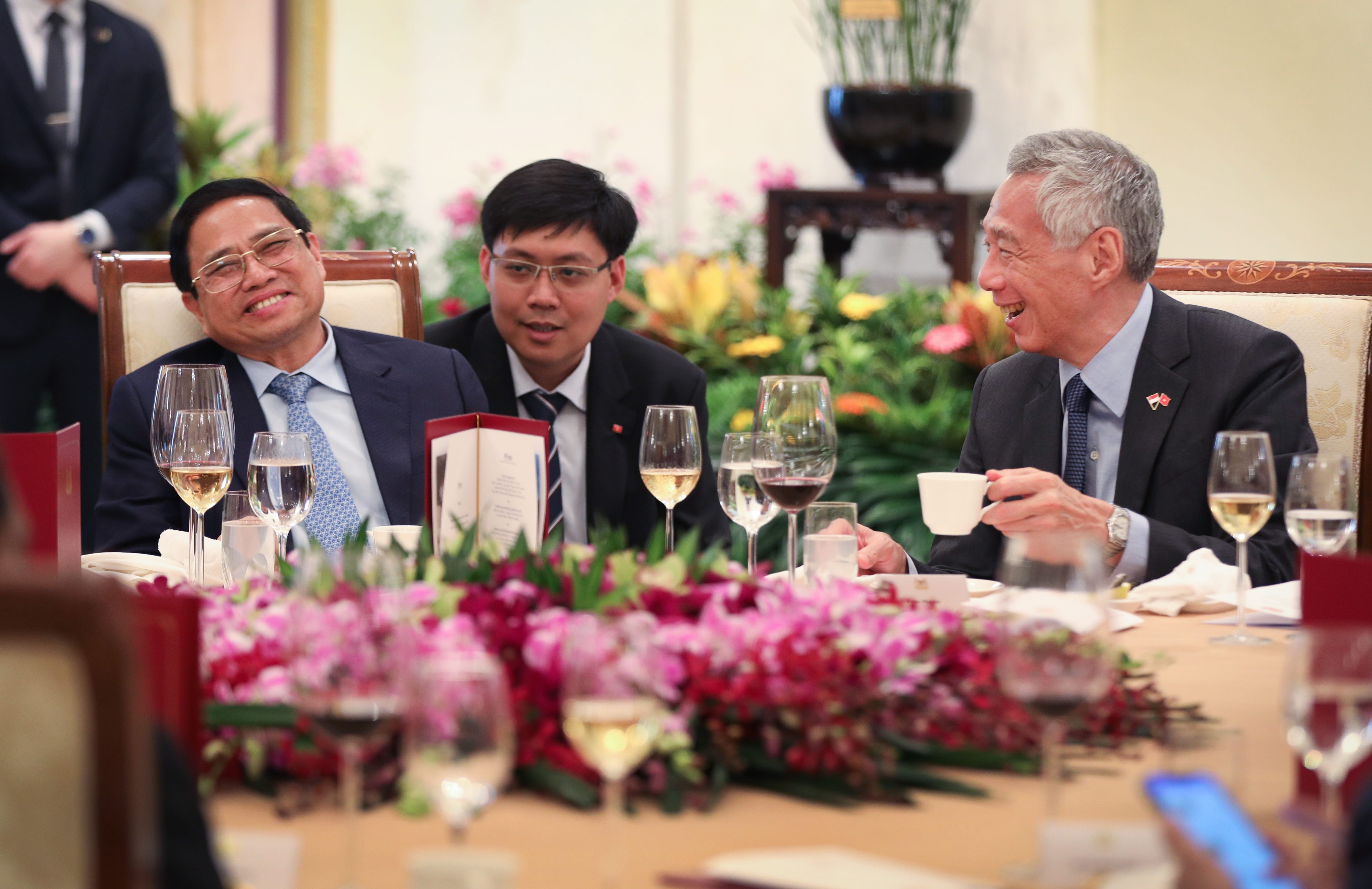 Lee Hsien Loong at dinner with other men in suits. Wine glasses and flowers adorn the table.
