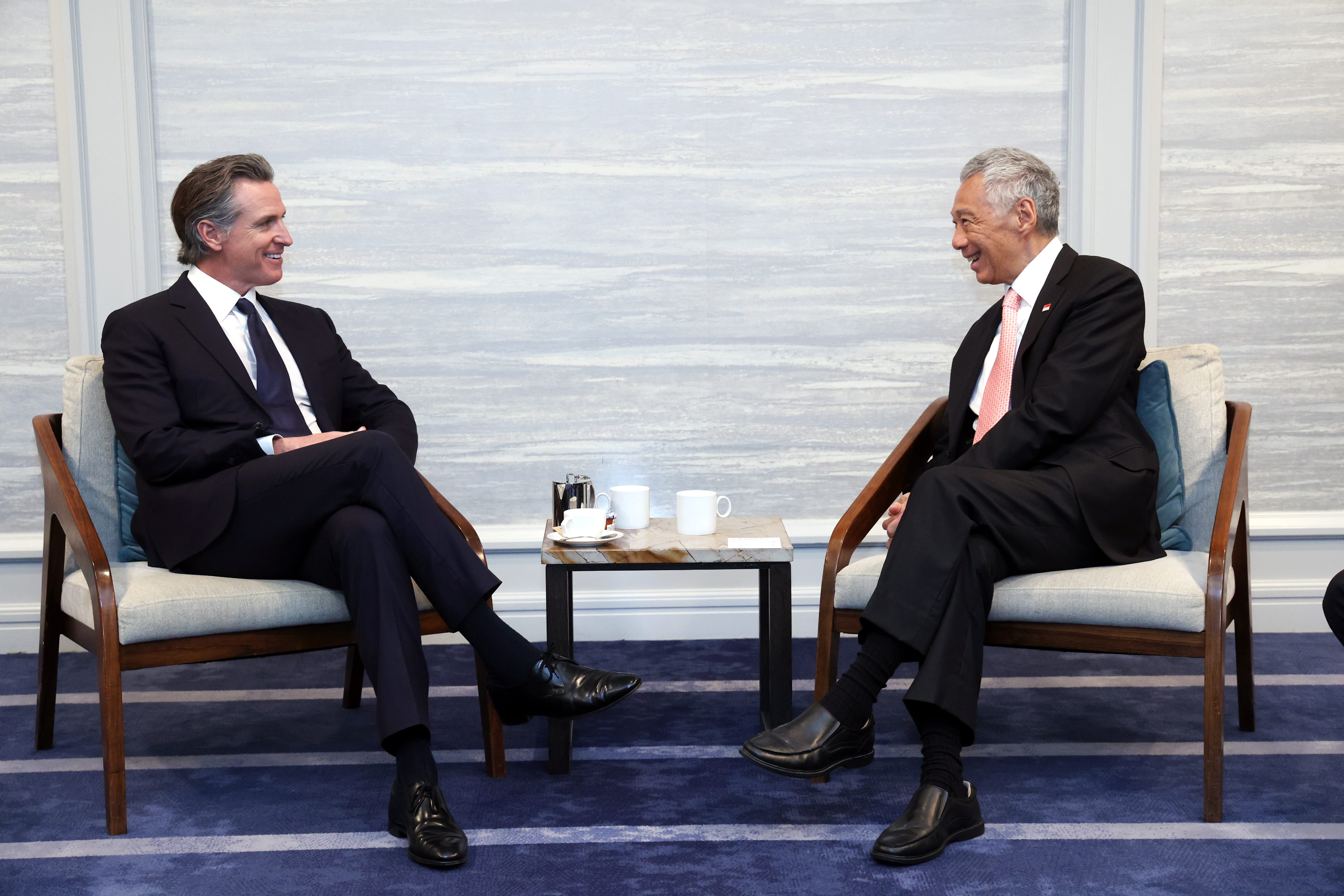 Gavin Newsom and Lee Hsien Loong seated, facing each other in suits. Coffee table between them.