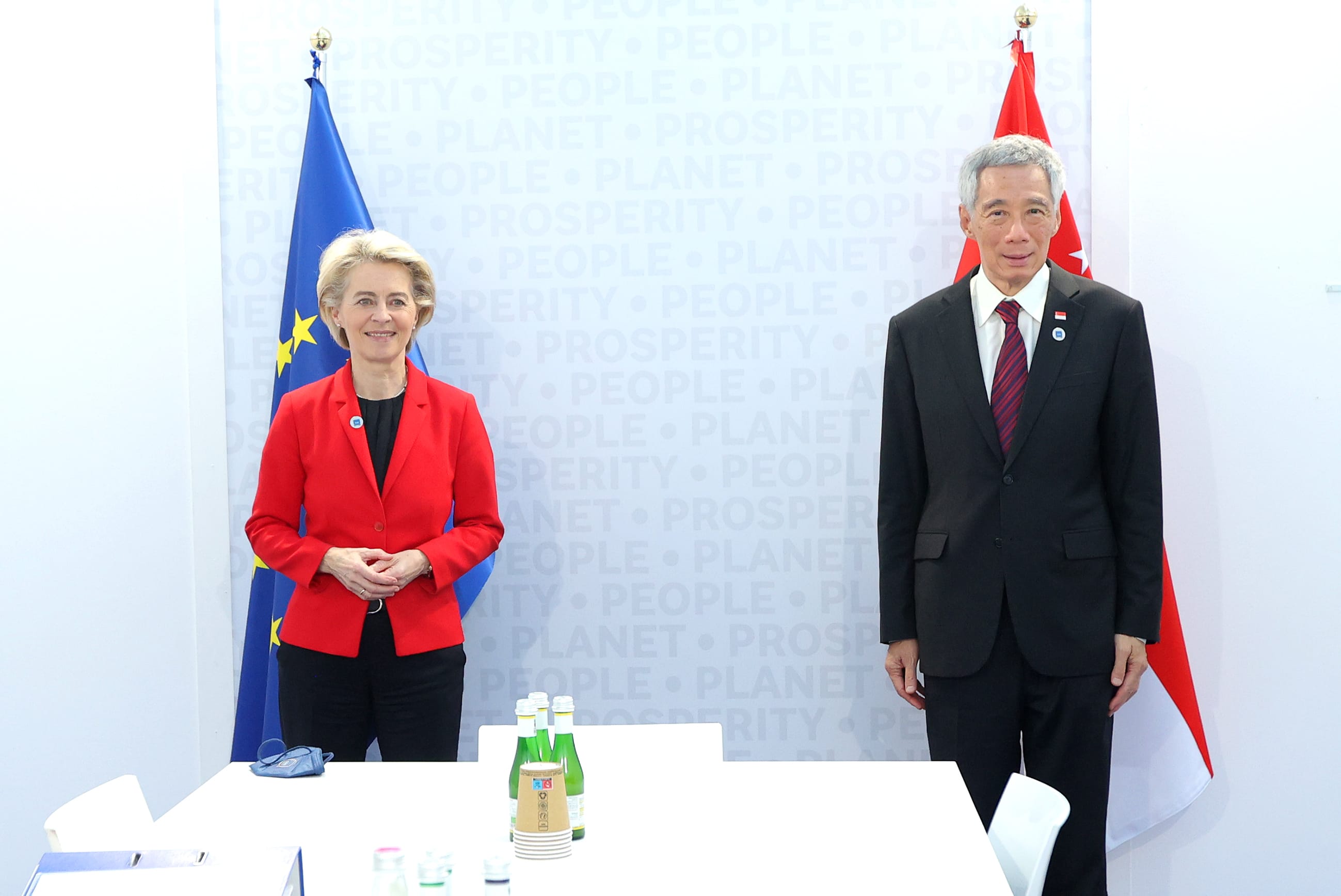 Ursula von der Leyen and Lee Hsien Loong stand with EU and Singapore flags.