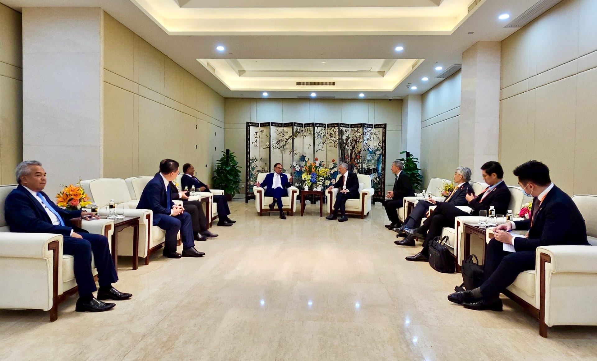 Group of people in suits seated in chairs, facing each other in a conference room.
