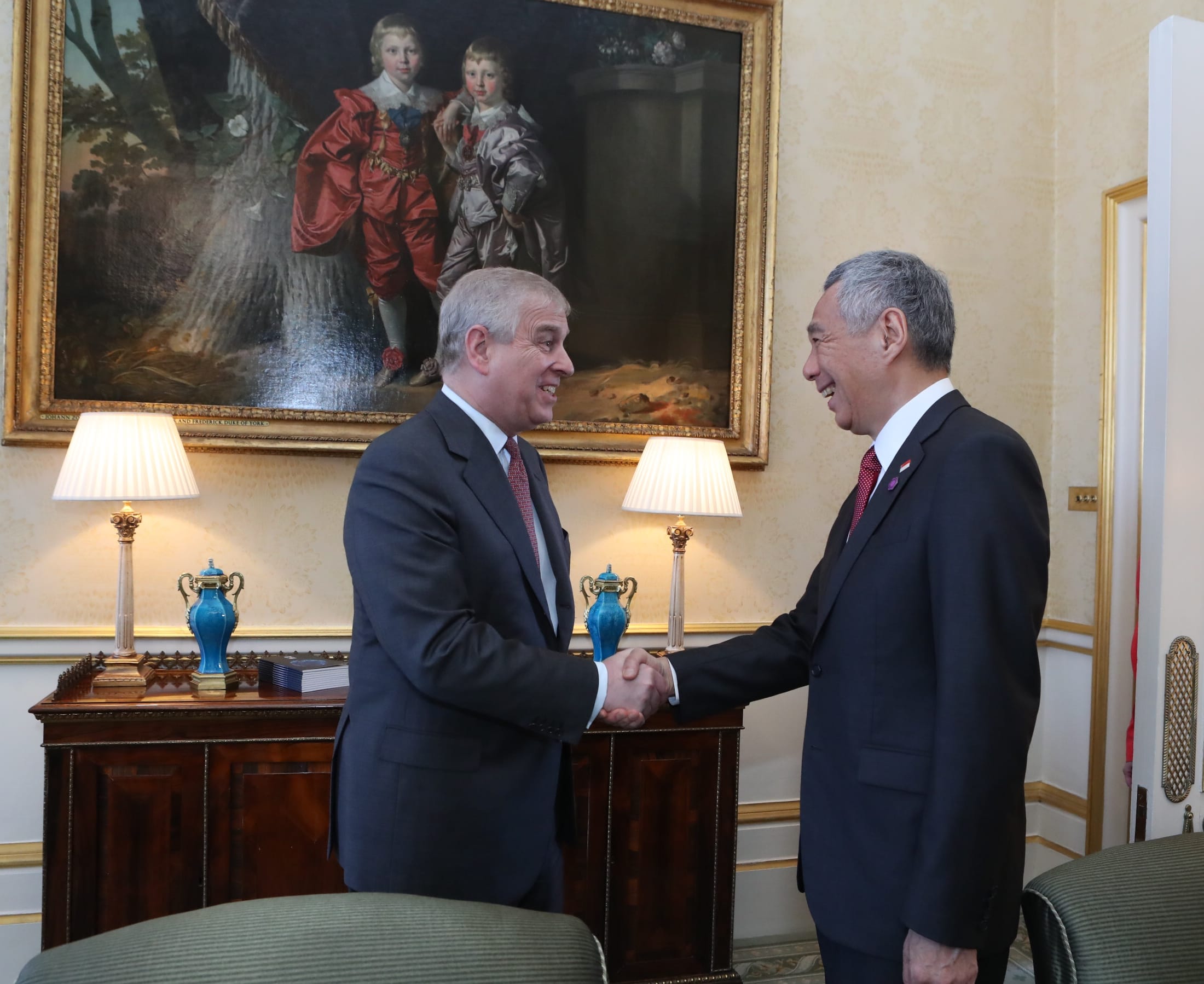 Prince Andrew shakes hands with Lee Hsien Loong in front of a painting.
