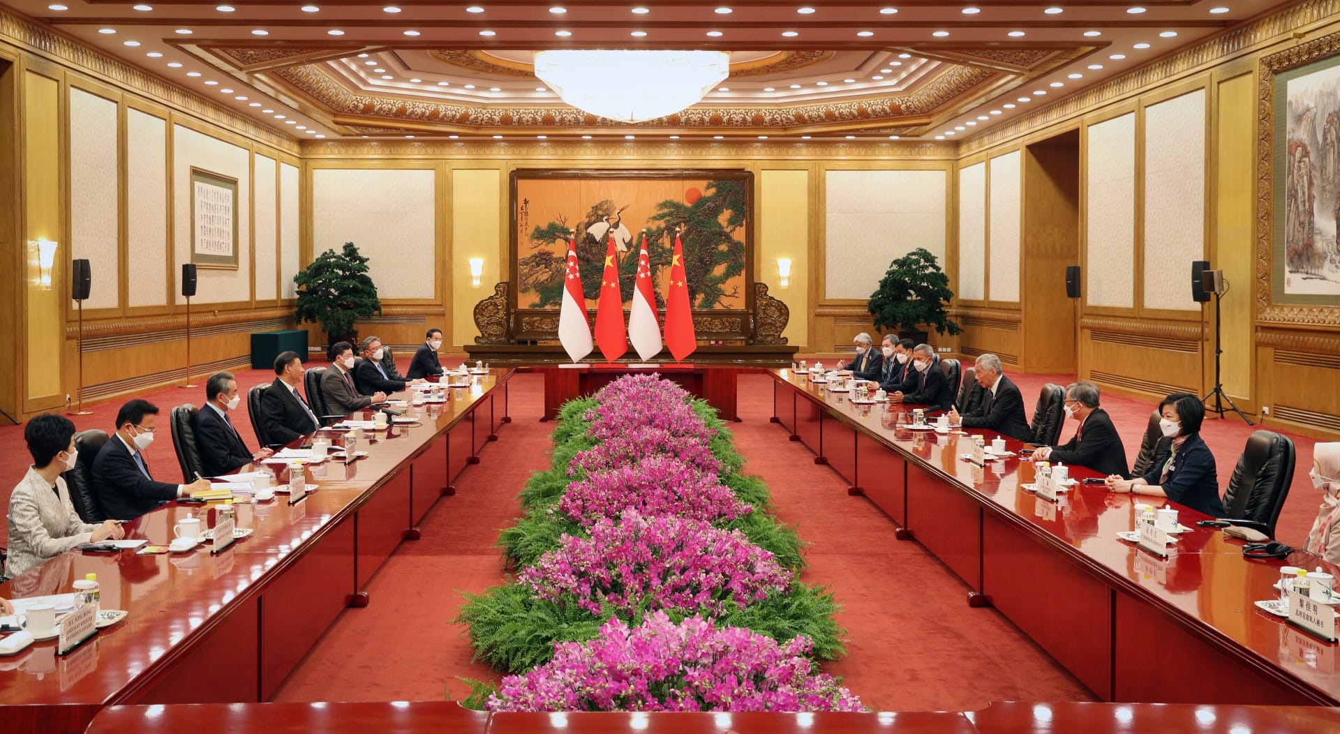 Formal conference room with Singaporean and Chinese flags flanked by officials at long tables.