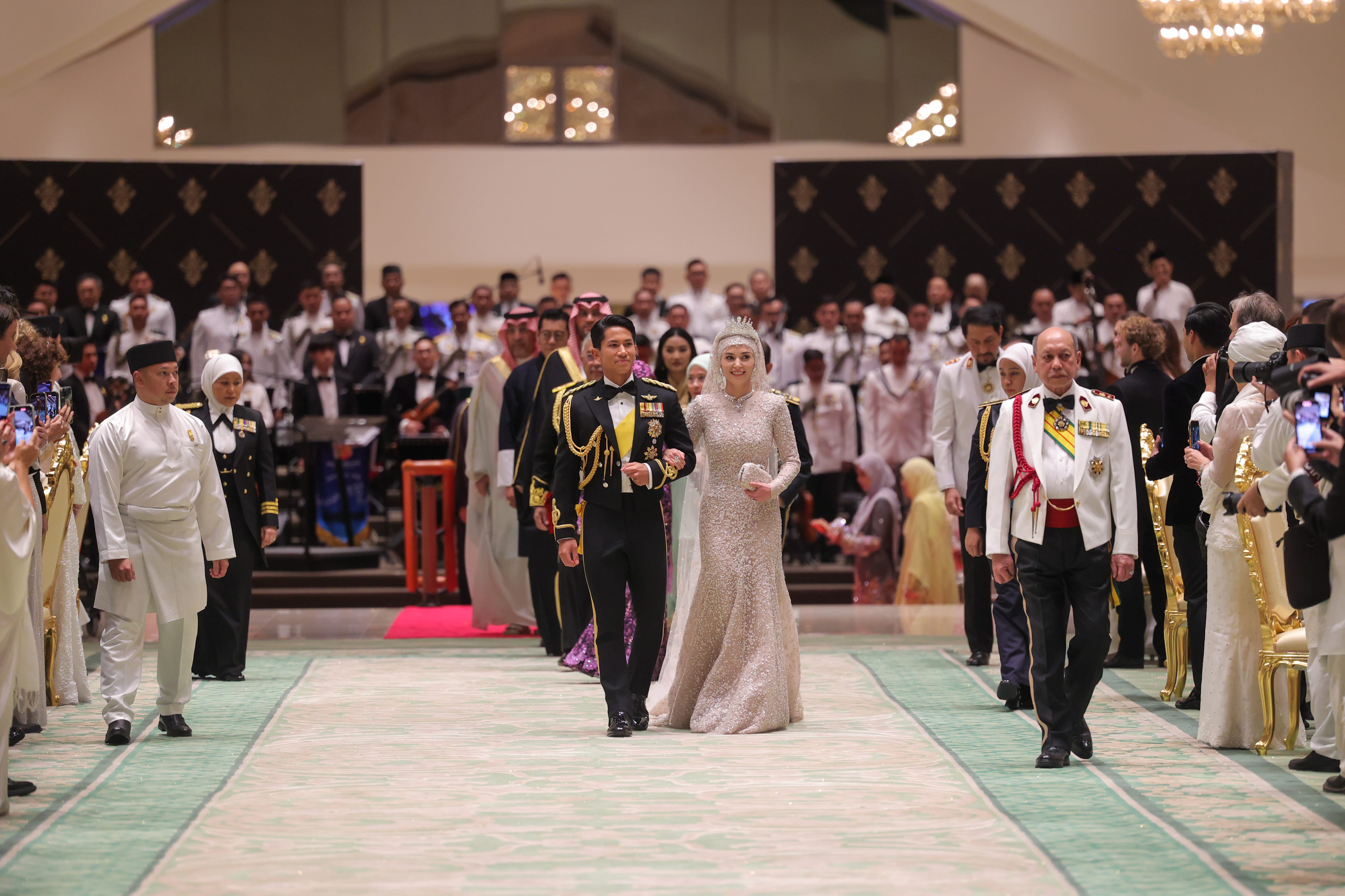 Wedding procession with Prince Mateen, bride in gown and tiara, and dignitaries.