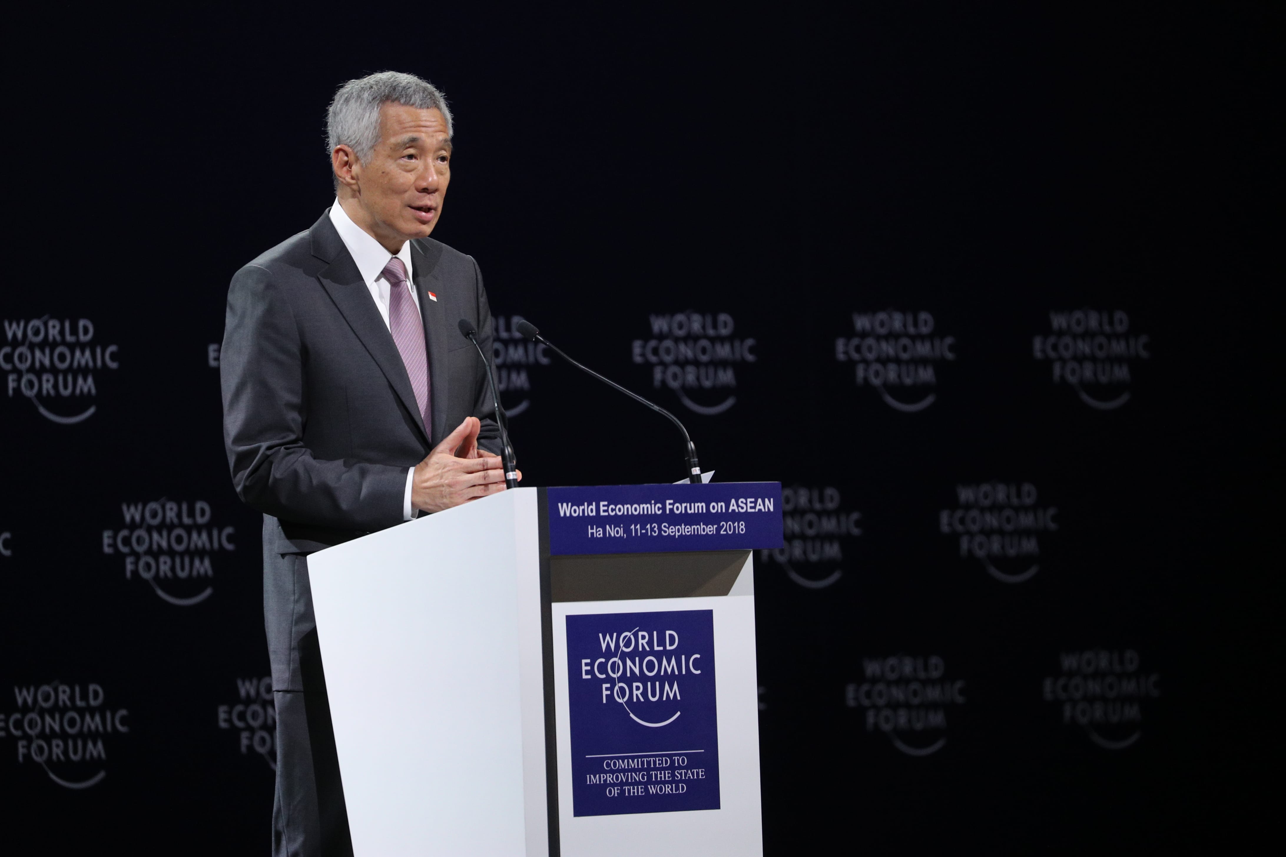 Lee Hsien Loong at World Economic Forum lectern, dark background with repeated logos.
