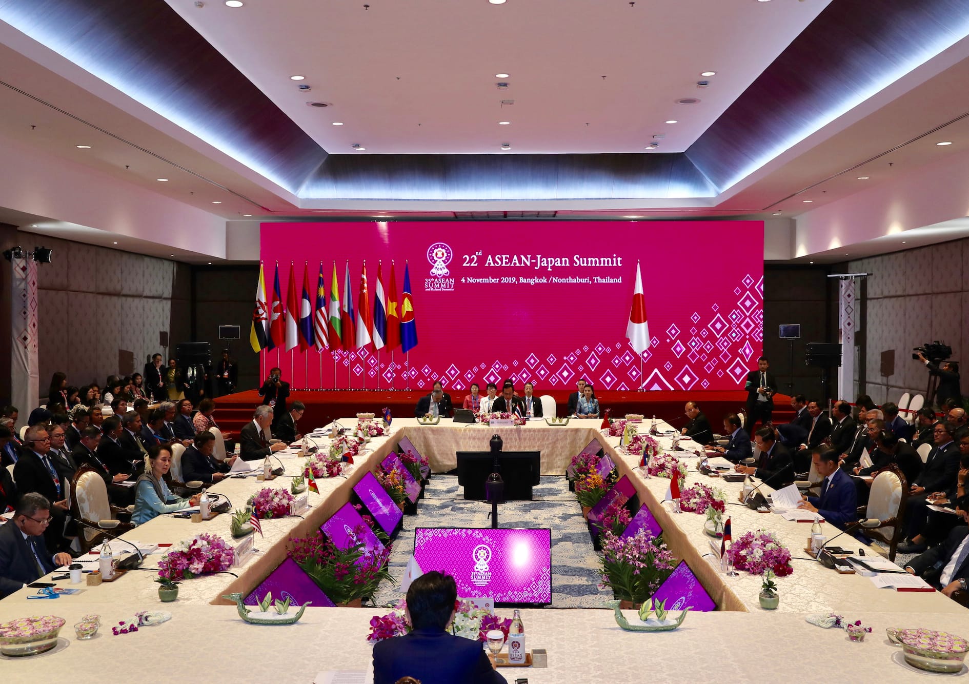 ASEAN-Japan Summit: People sit at a large table, facing flags and a pink banner.