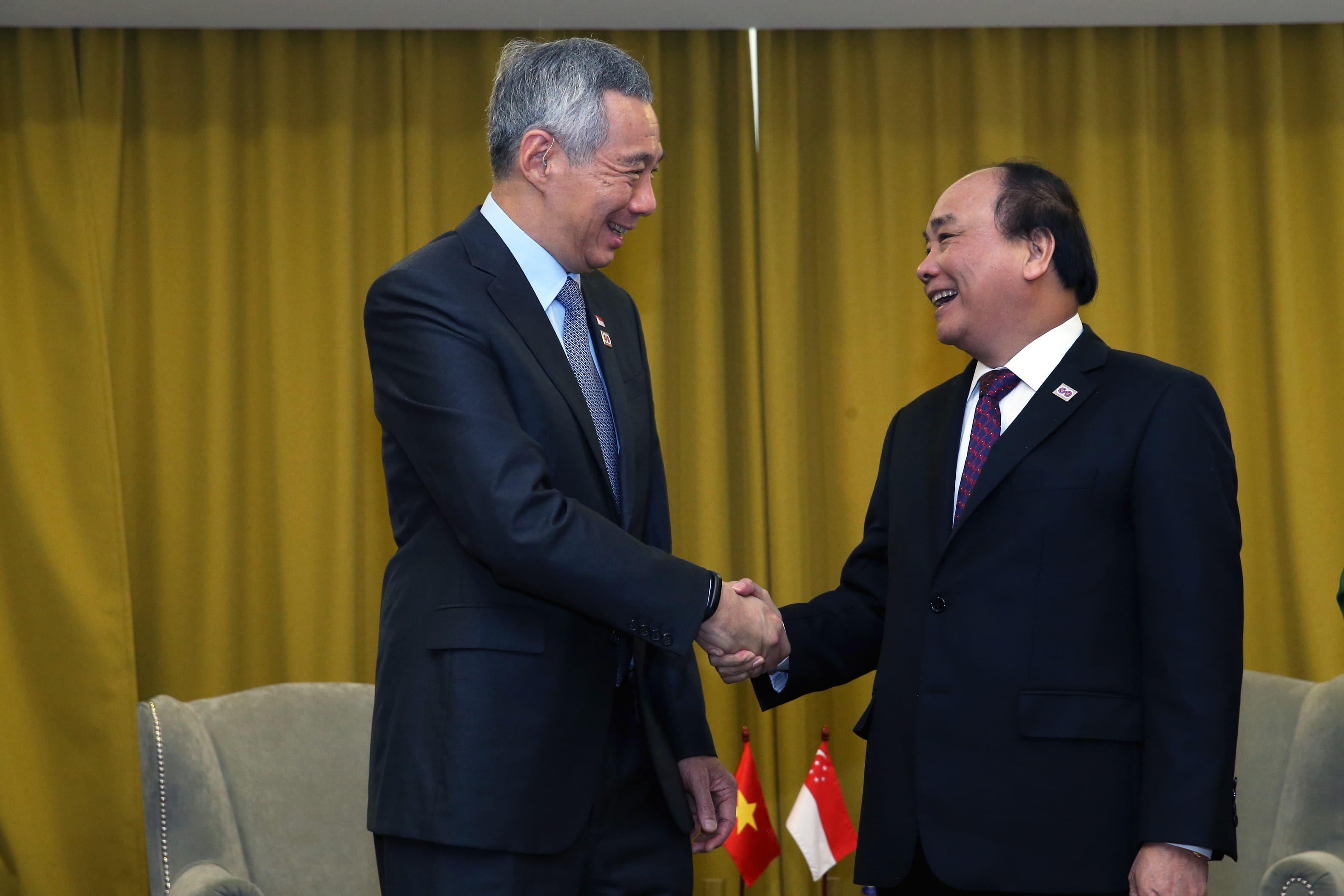 Lee Hsien Loong and Nguyen Xuan Phuc shake hands in front of flags.