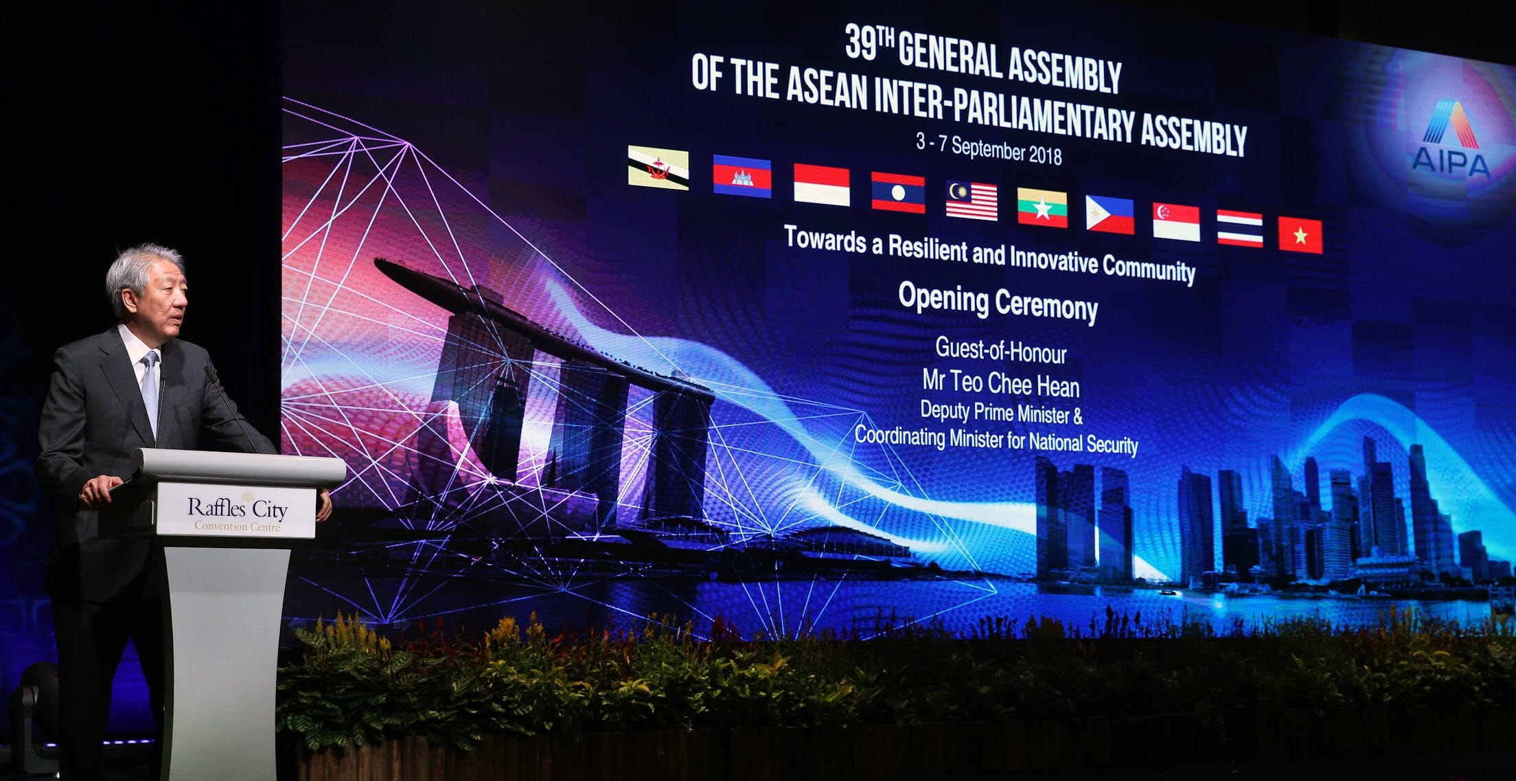 Man at podium with Raffles City logo; "39th General Assembly" on screen behind him.