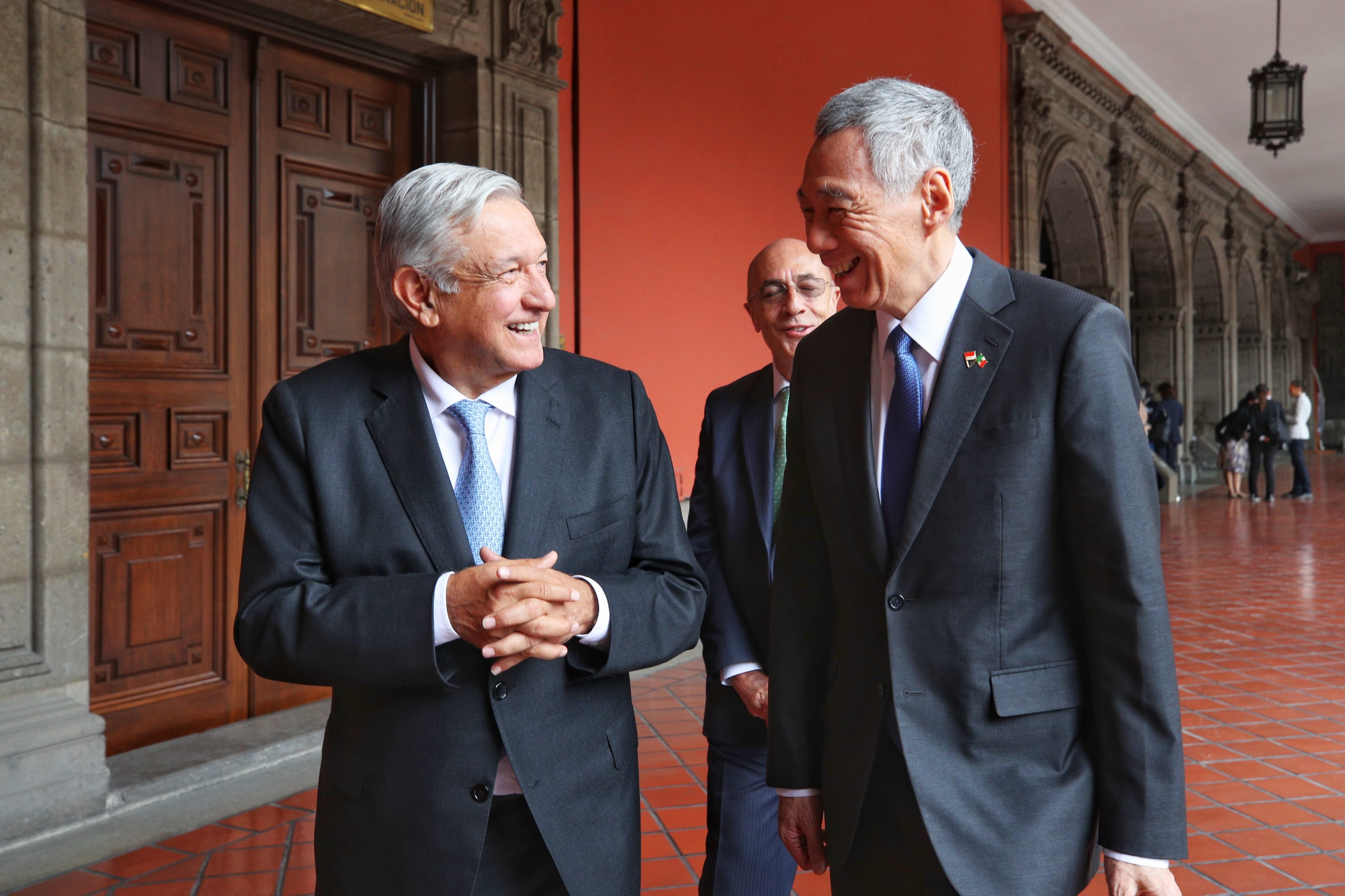 Andrés Manuel López Obrador and Lee Hsien Loong smile, wearing suits with flags on lapels.