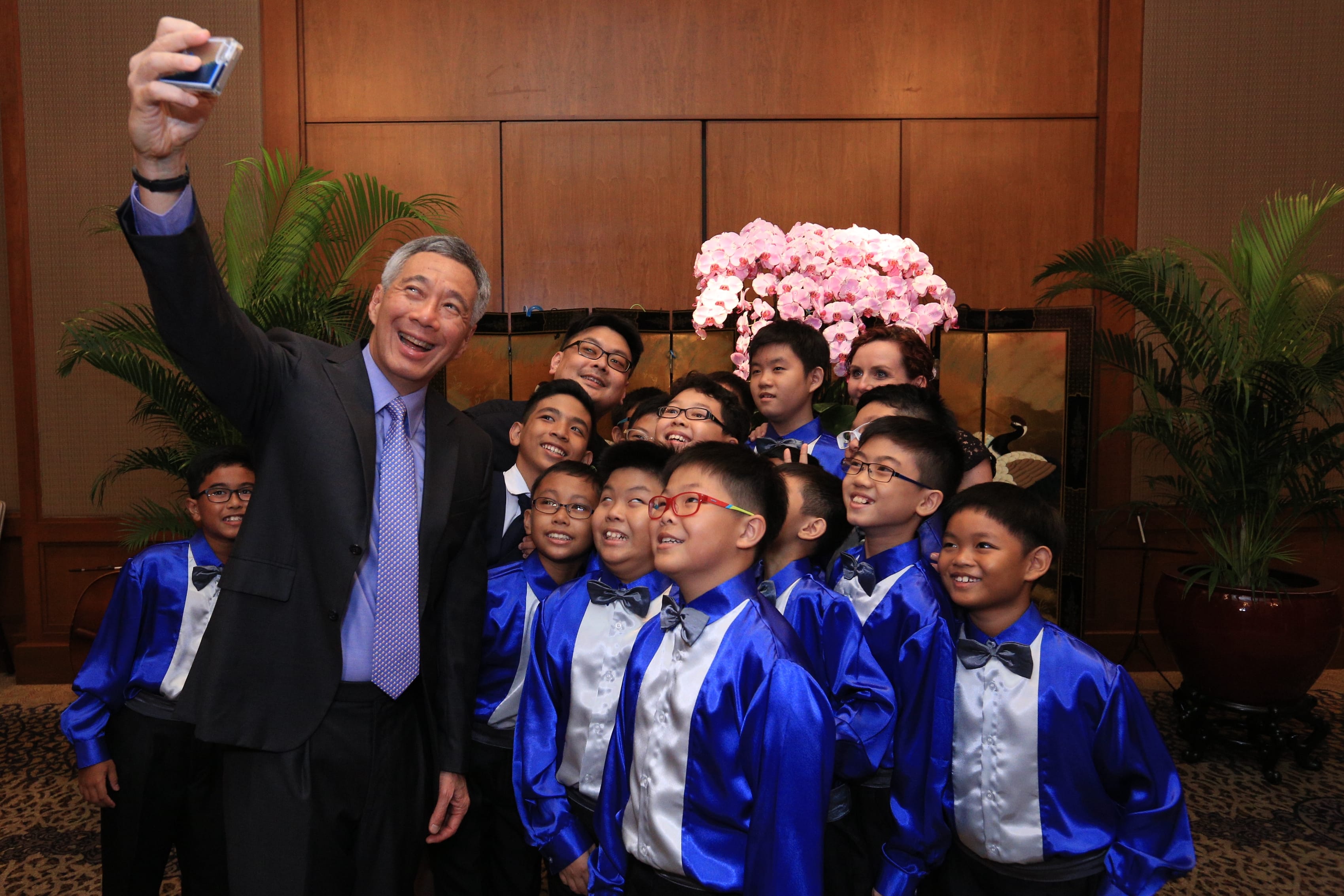 Lee Hsien Loong takes selfie with a group of children in matching blue shirts.