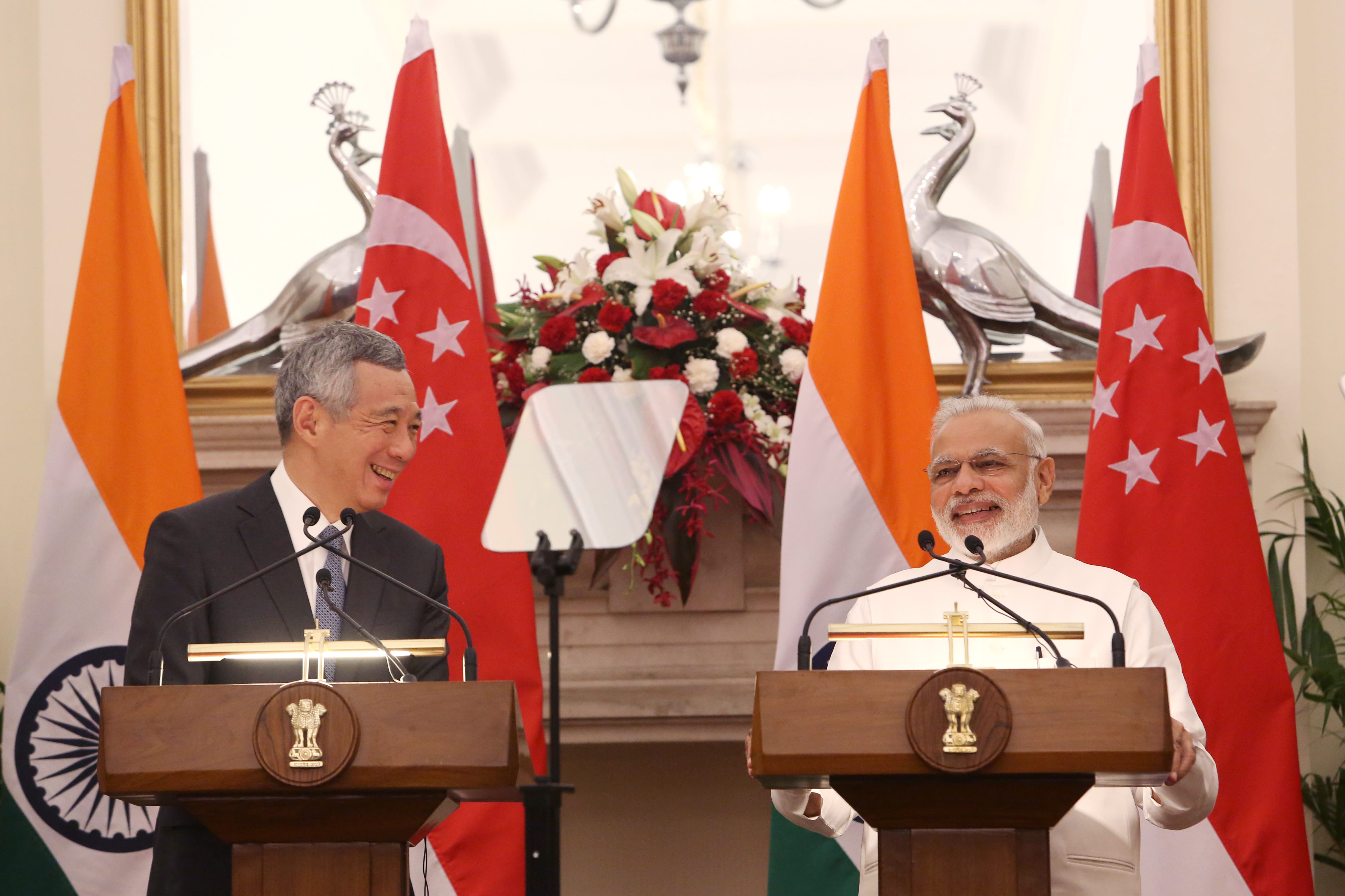 Lee Hsien Loong and Narendra Modi stand at podiums flanked by Singaporean and Indian flags.