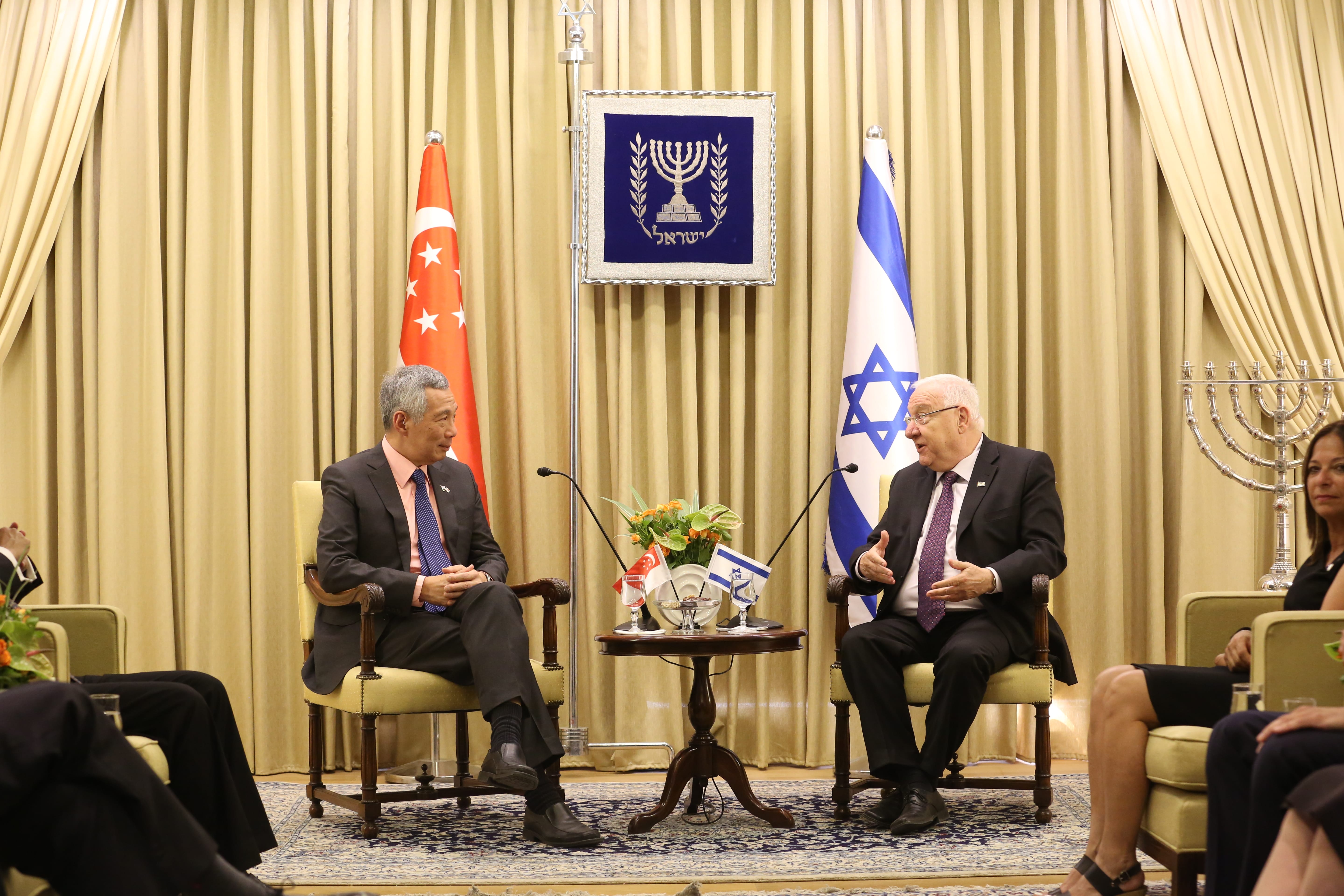 Lee Hsien Loong and Reuven Rivlin seated near Singapore and Israeli flags.