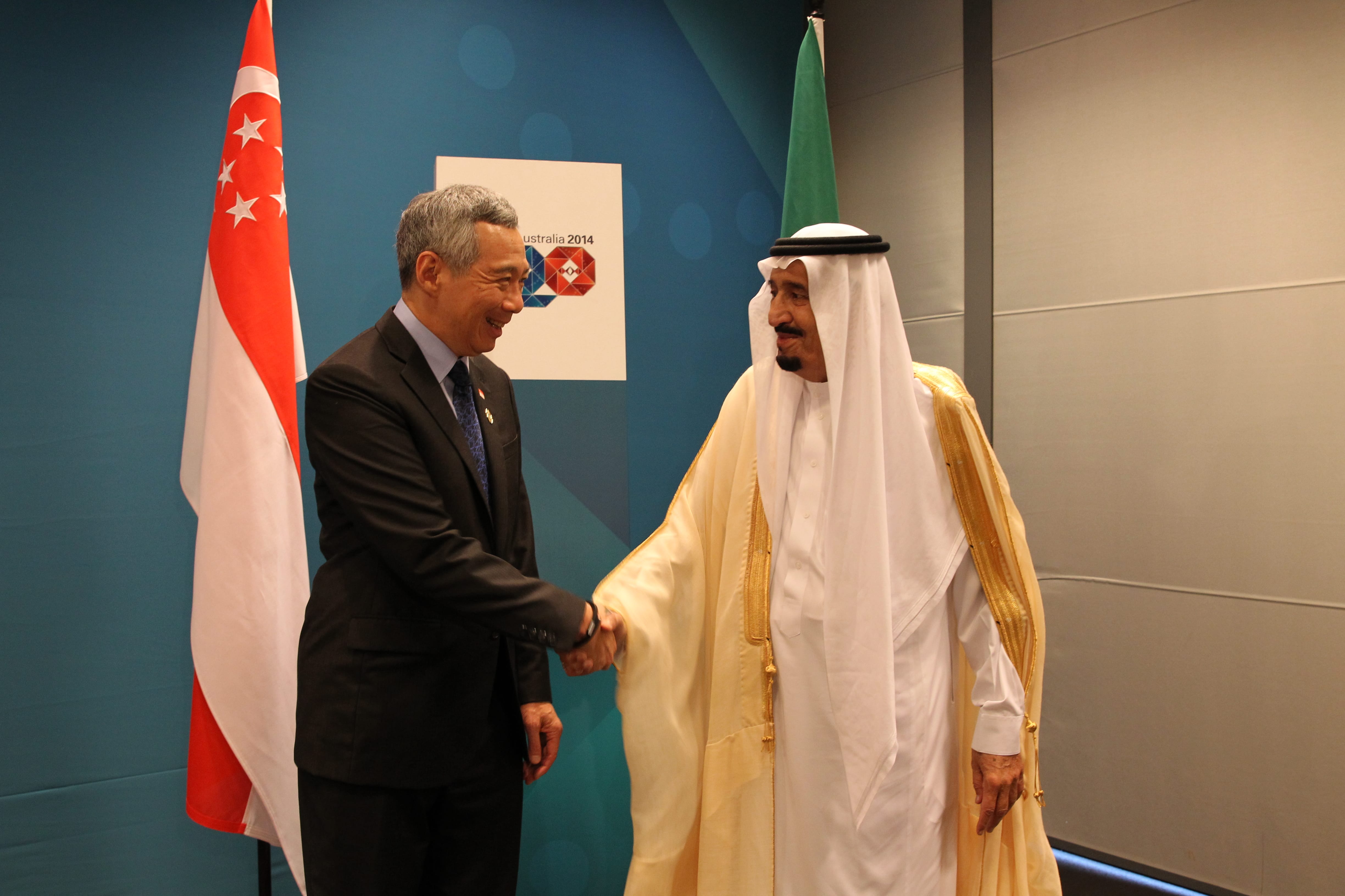 Lee Hsien Loong and King Salman shaking hands near Singapore and Saudi Arabia flags.
