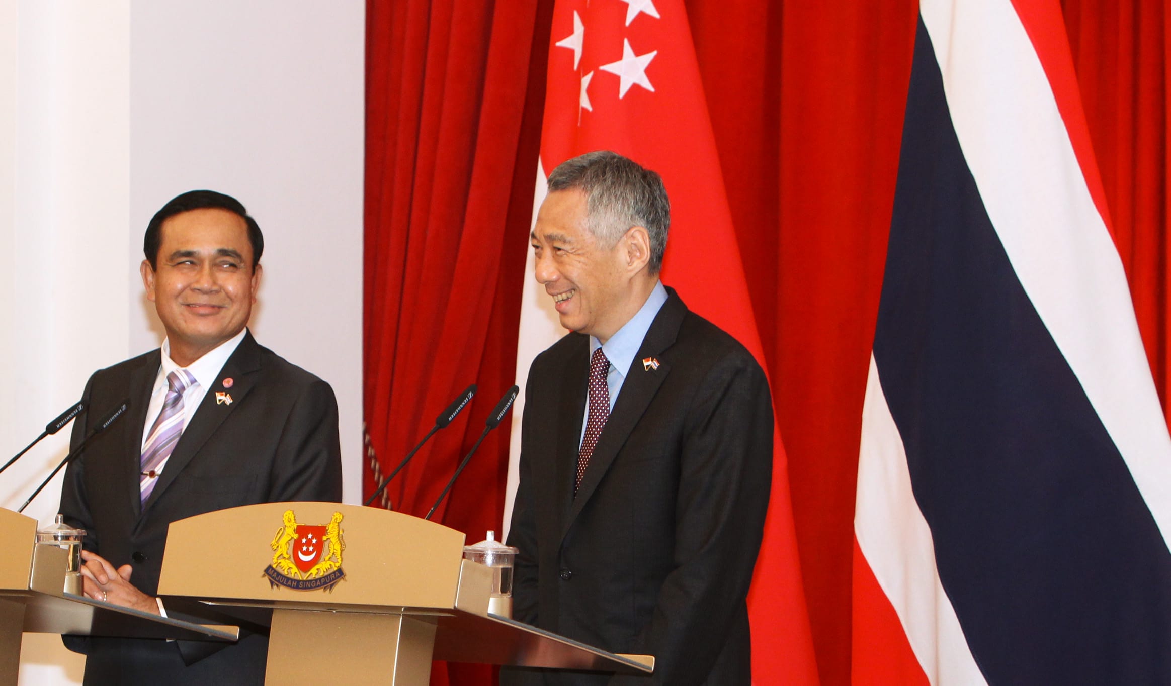 Lee Hsien Loong and Prayut Chan-o-cha at lecterns with Singapore and Thailand flags.