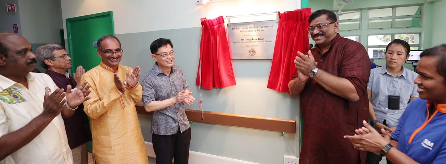 Group applauds unveiling of "Sree Narayana Mission (Singapore)" plaque with red curtain.
